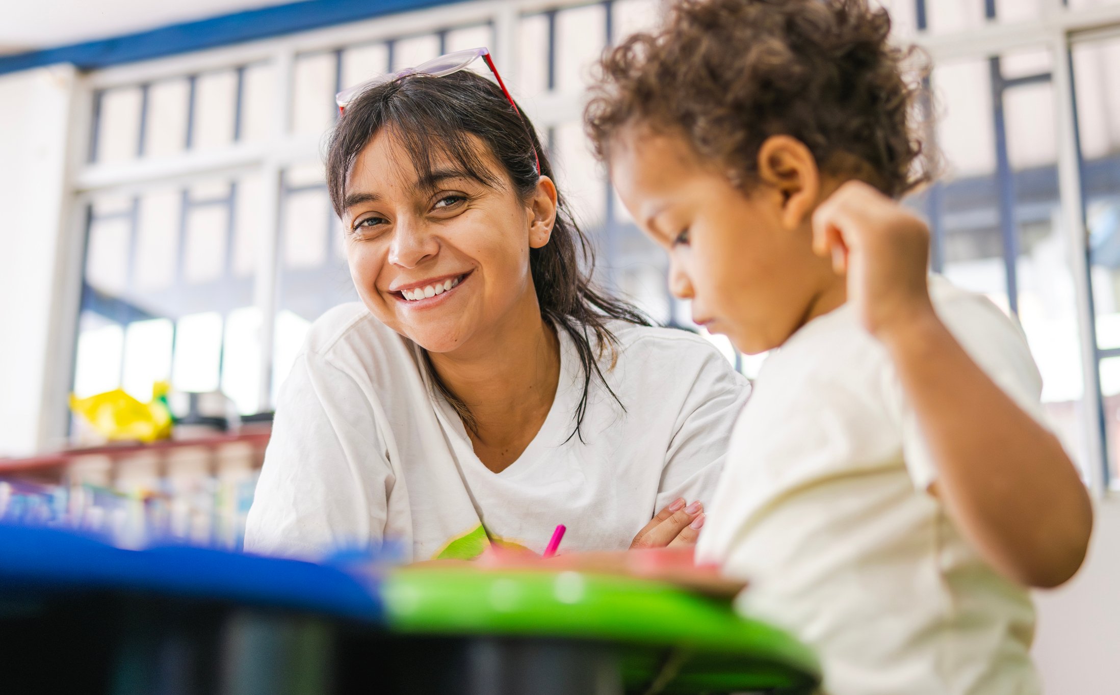 Female early childhood educator working at a table with child