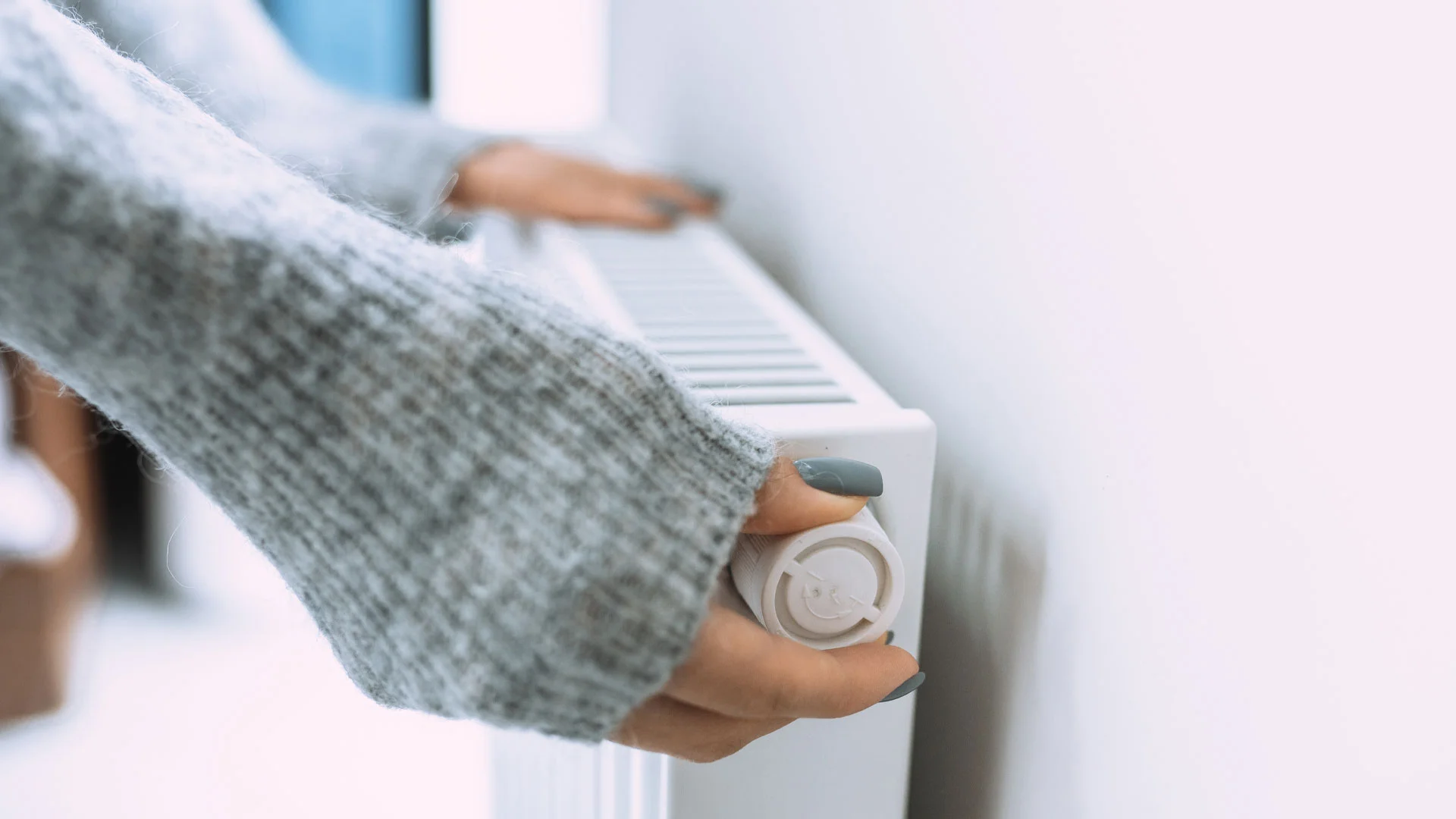 Woman turning on a radiator in her home in New Zealand.