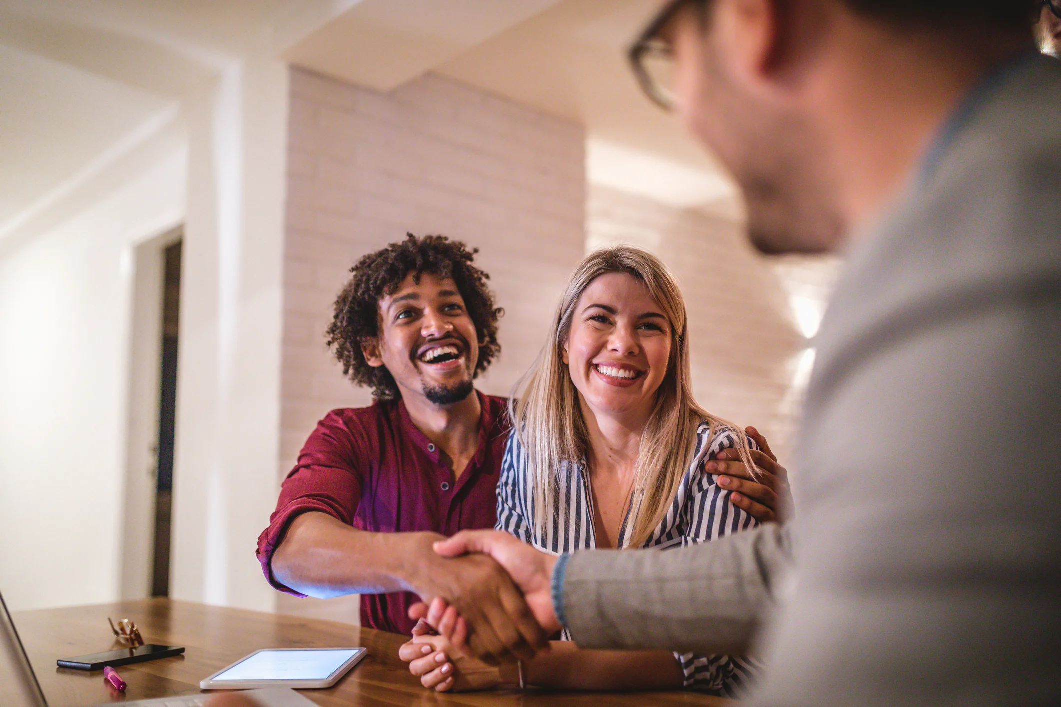 Happy young couple shaking hands with real estate agent for an agreement being made