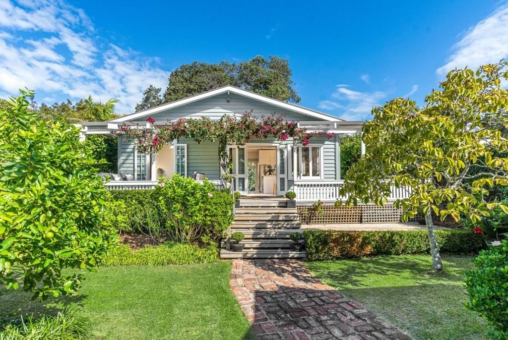 Light blue cottage with pink and red bougainvillea over the entrance