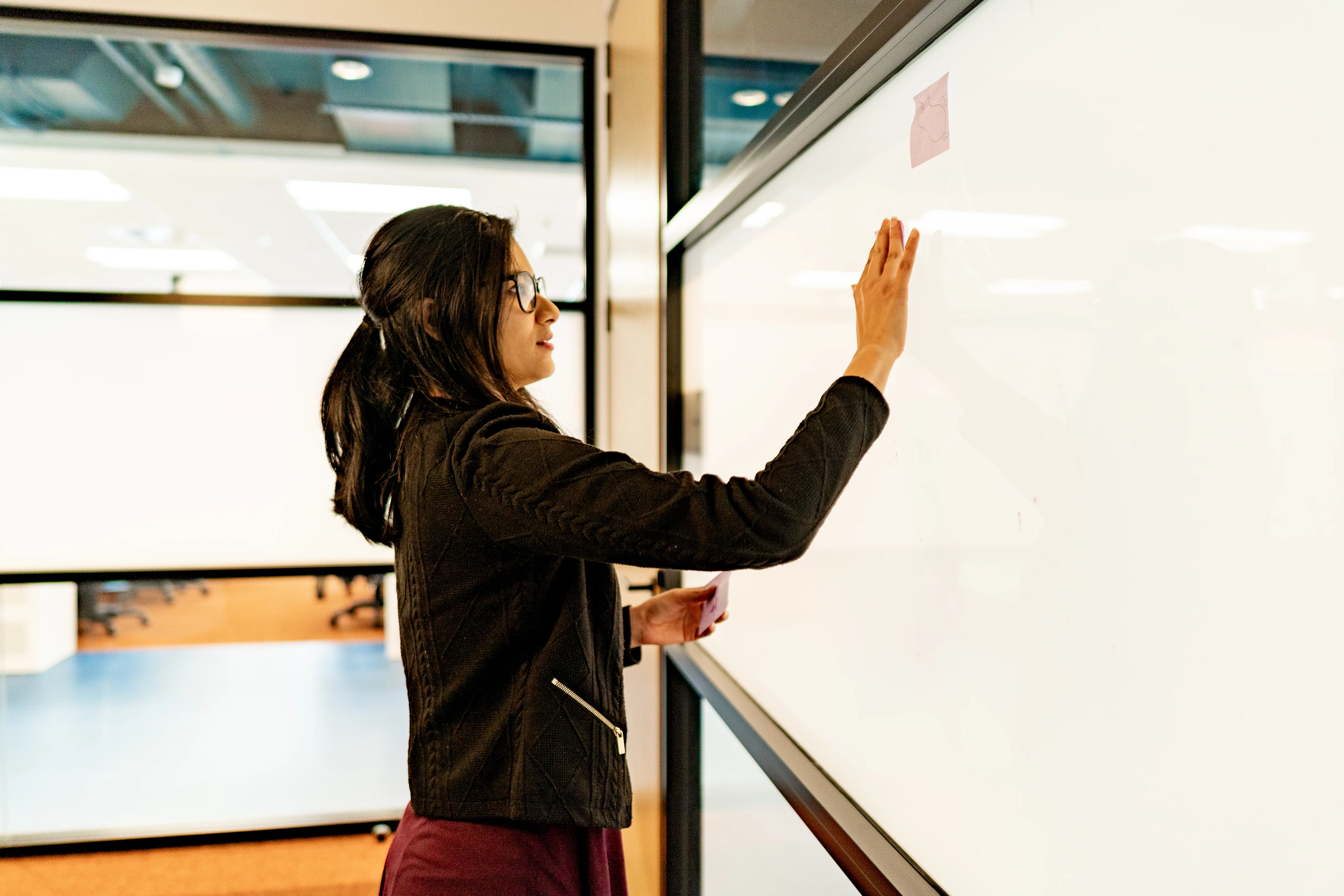 Woman writing on whiteboard in board room.