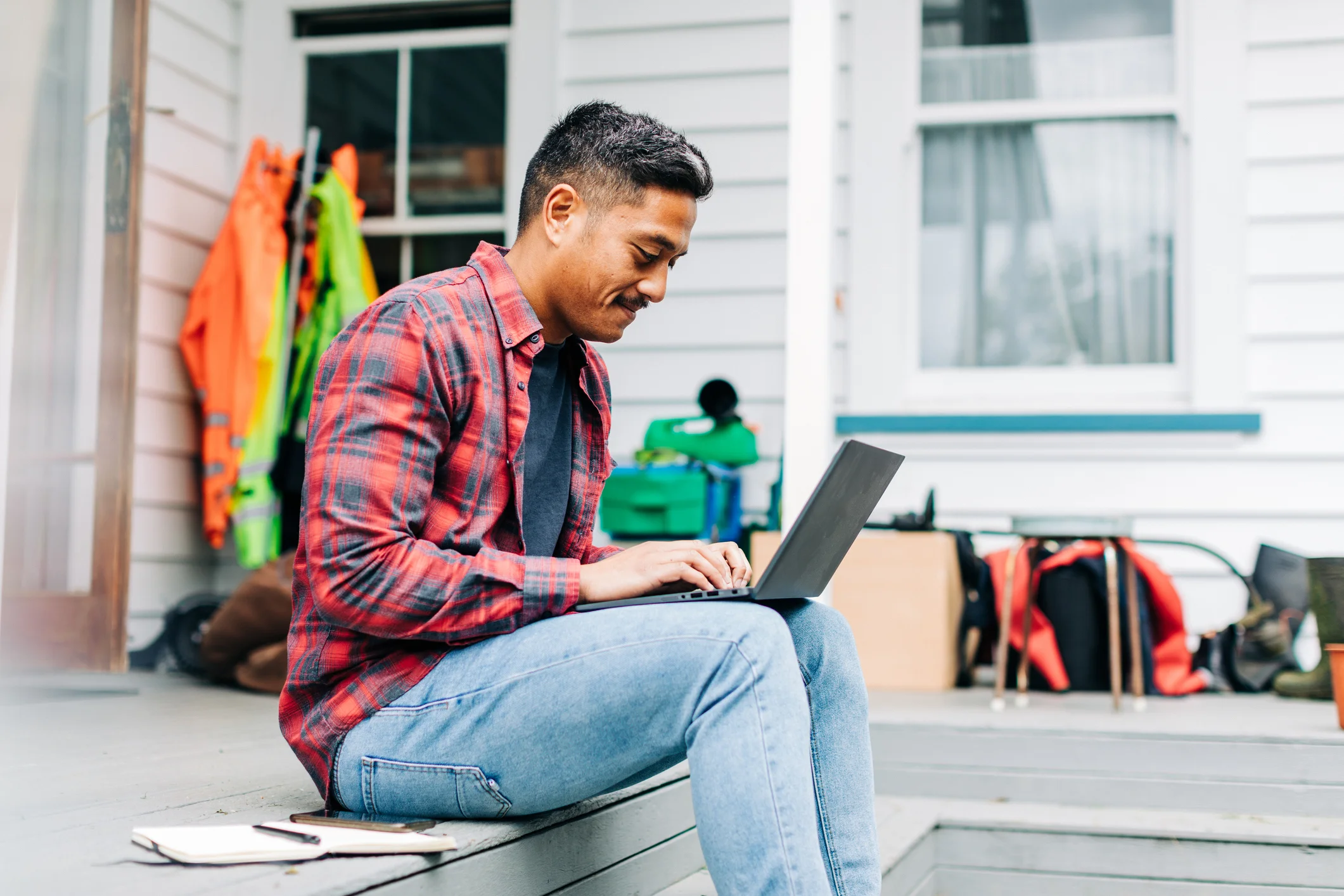 Man sitting outside working on a laptop while listing a job ad