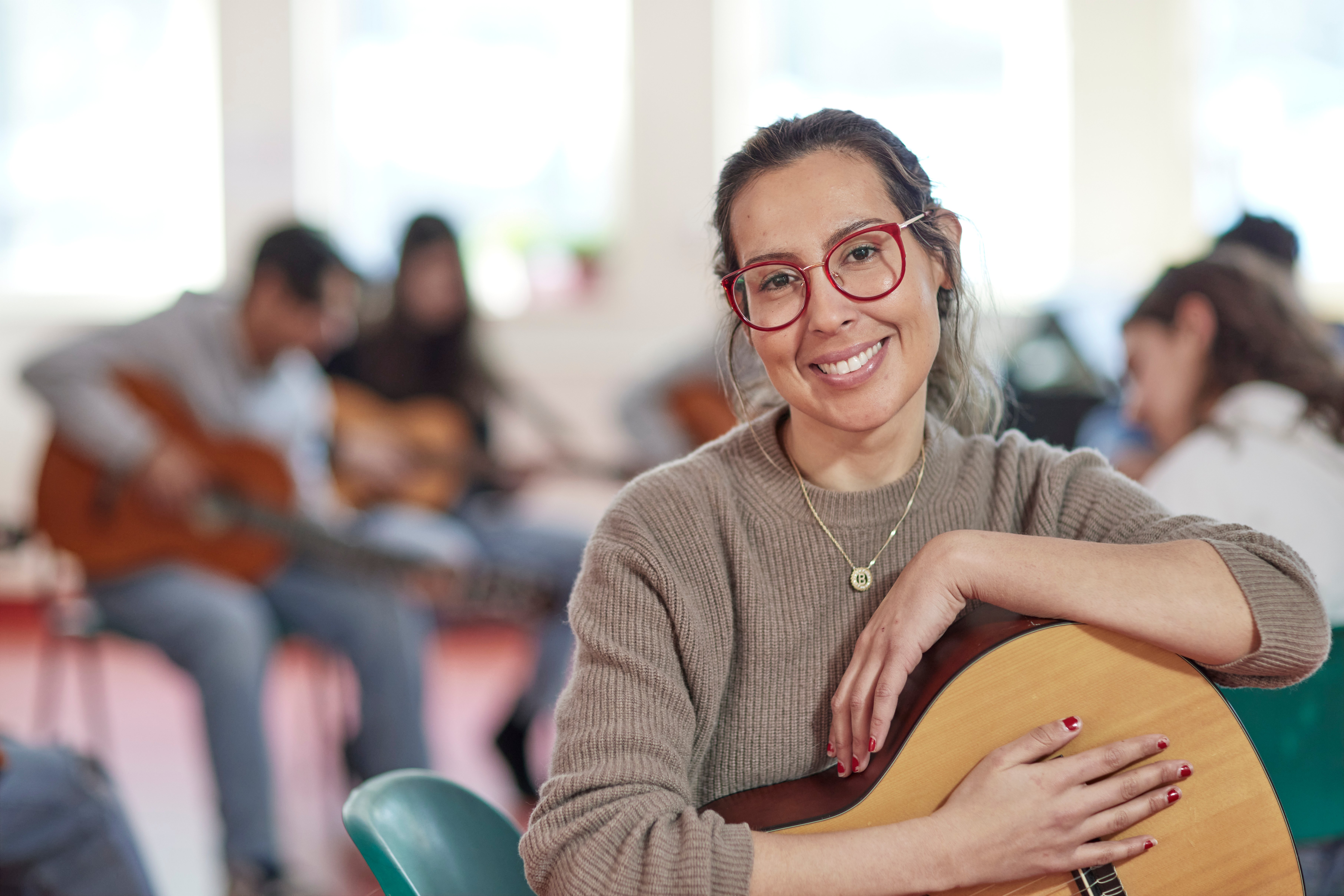 Female teacher sitting on chair with students in the background