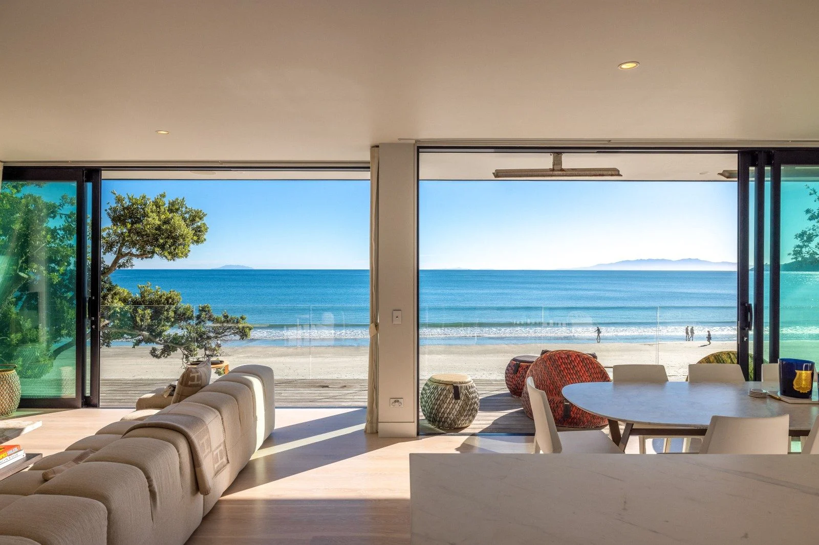 Sleek modern beachfront home with floor-to-ceiling windows and uninterrupted ocean views, just steps away from the sandy shoreline.