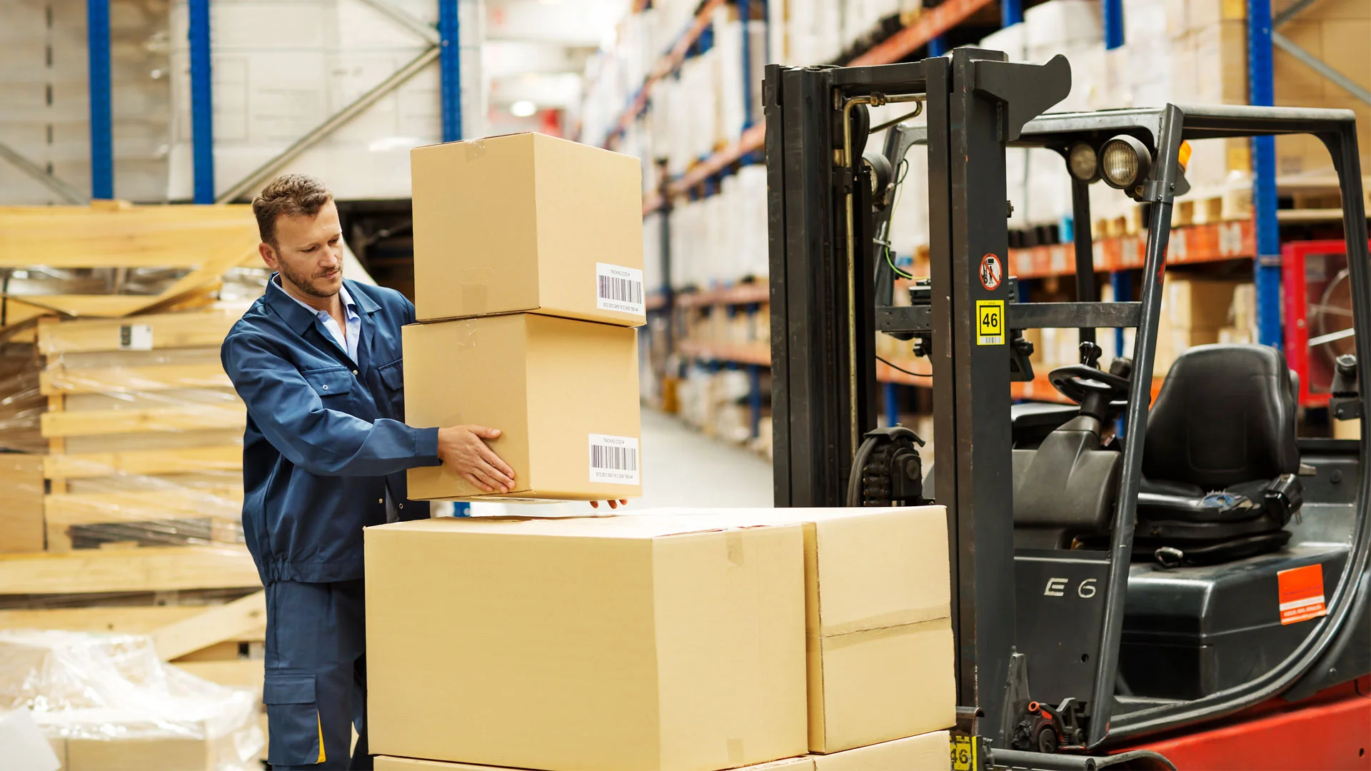 Male warehouse employee stacking boxes onto a forklift truck.