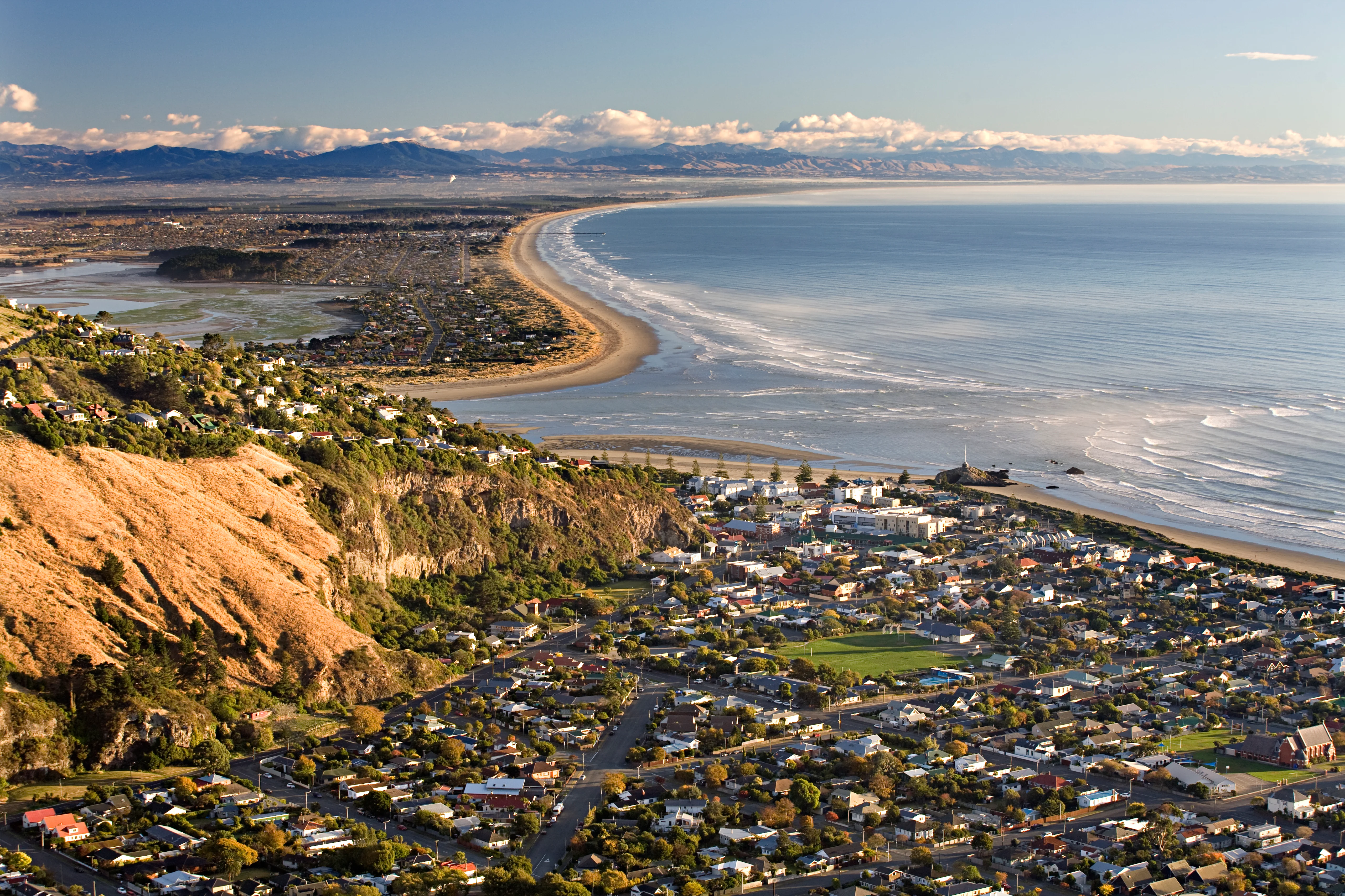 Sunny morning at beach town near river mouth. High view overlooking the coast with mountains and houses around the sea.