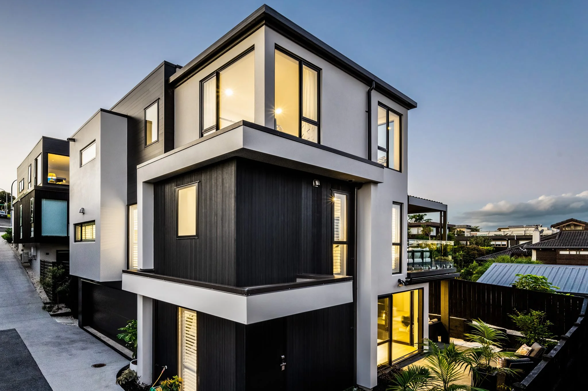 Modern townhouse with large illuminated windows at dusk