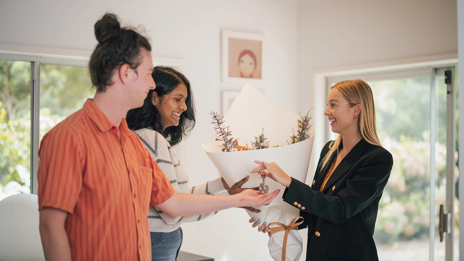 Real estate agent handing couple flowers. How much do real estate agents make in NZ?