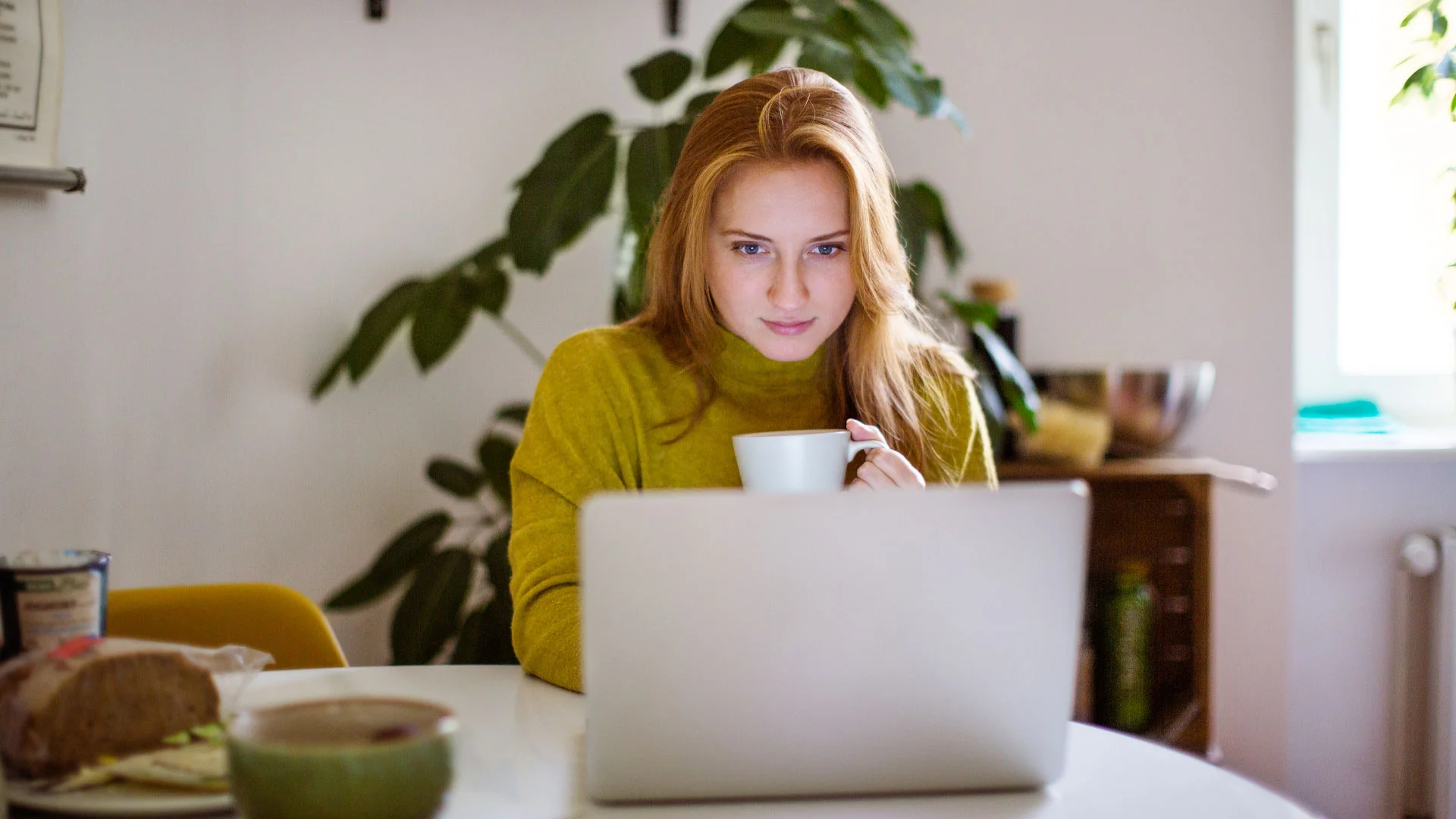 Young woman reading through Trade Me Jobs' free online salary guide on her laptop.