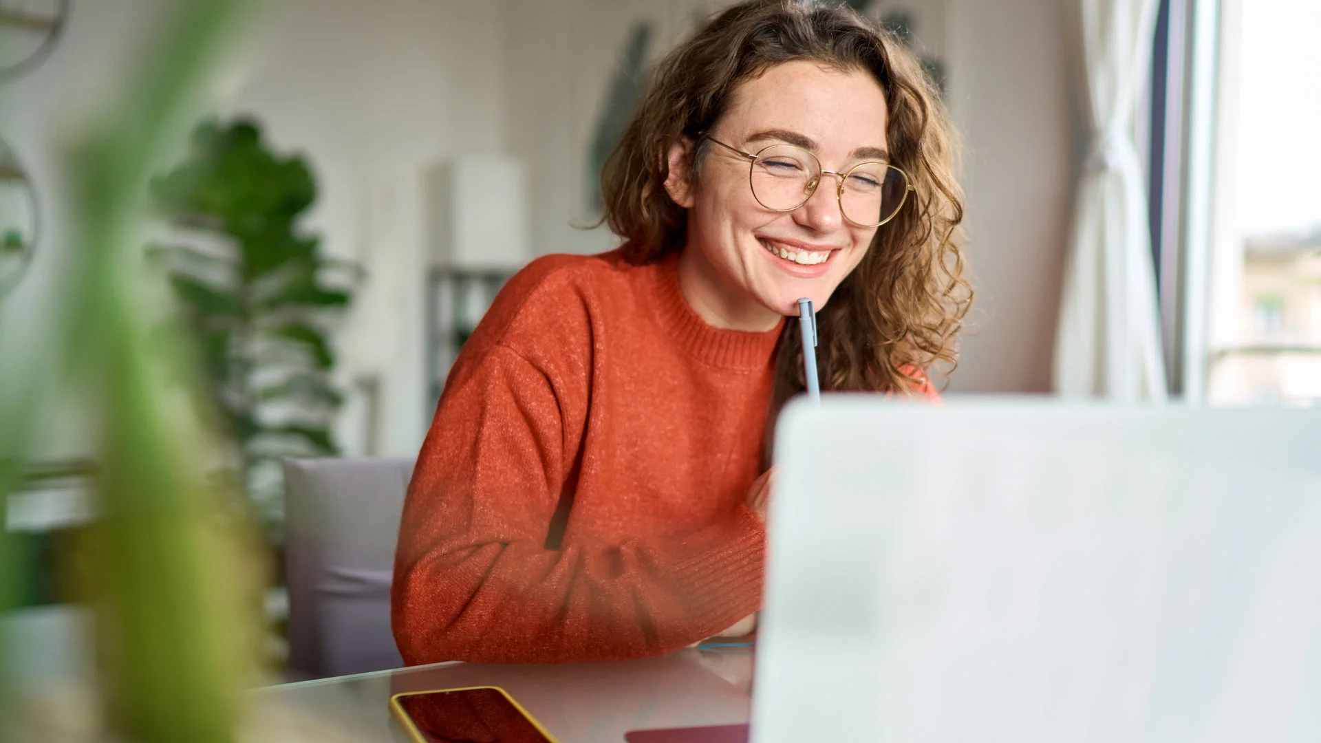 Female student working at a laptop in her room.