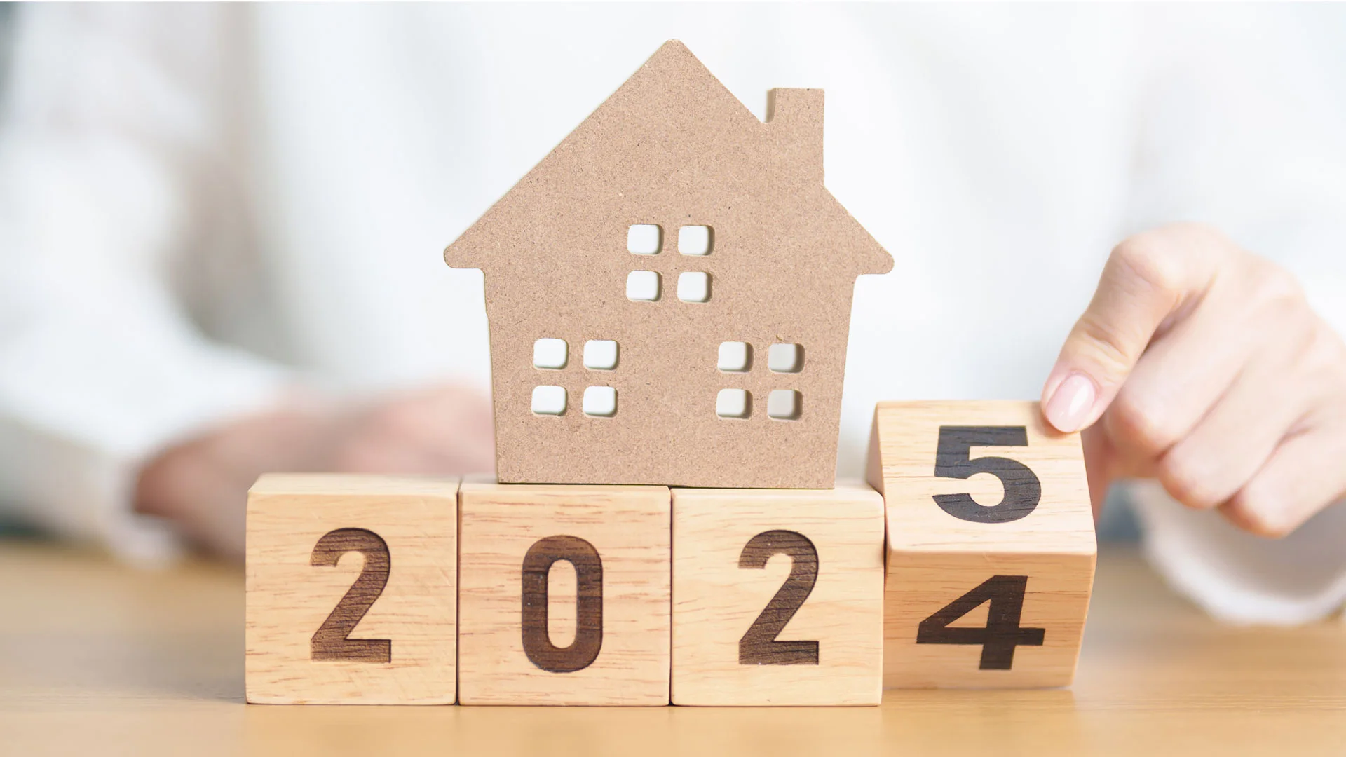 A set of cubes with showing the year ticking over from 2024 to 2025, with a model of a property on top of the cubes.