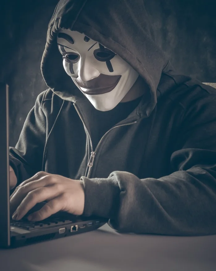 A man on a laptop with a clown mask