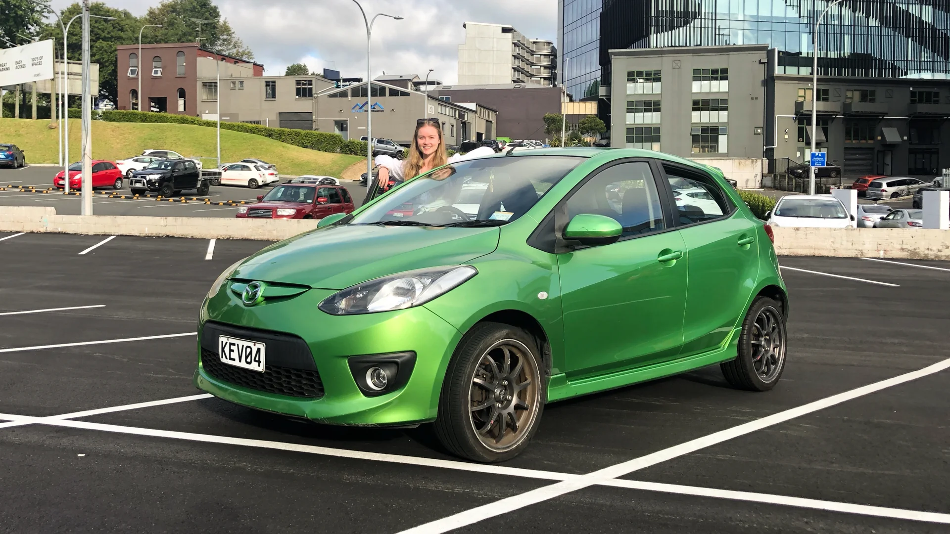 Young lady standing next to green car
