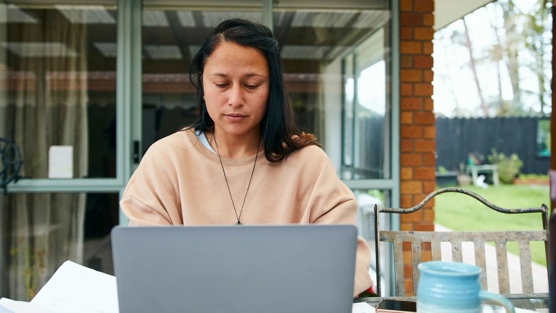 Woman working on a laptop on the deck of her house.