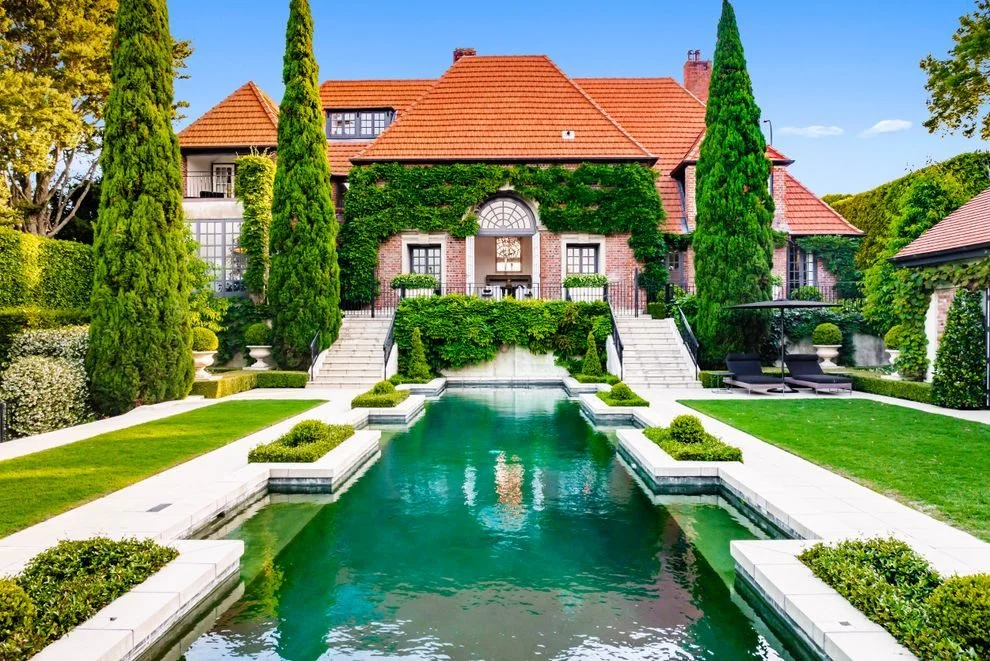 Grand Remuera estate in Auckland, ranked among the most expensive houses in New Zealand, with a formal pool, manicured gardens, and ivy-covered brick architecture.