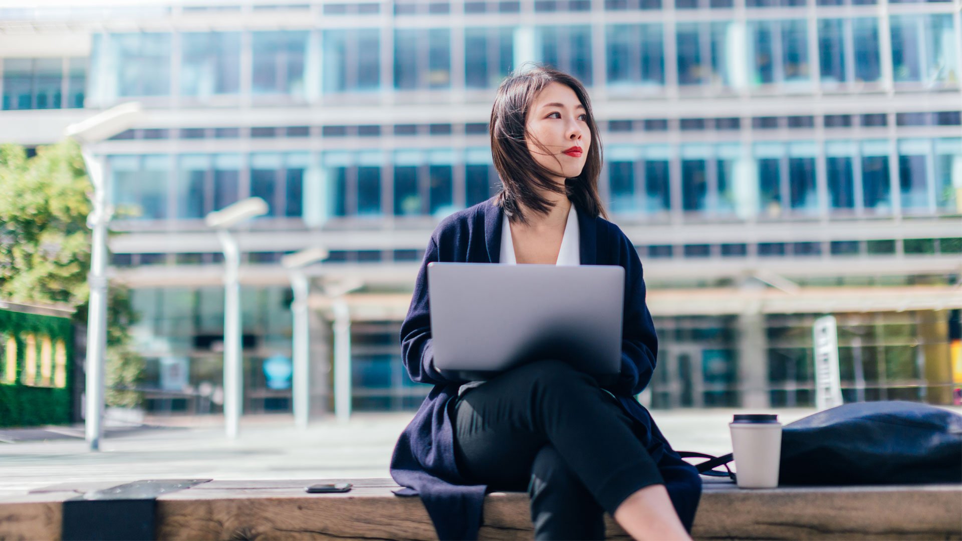 Businesswoman sitting outside an office looking hopeful.
