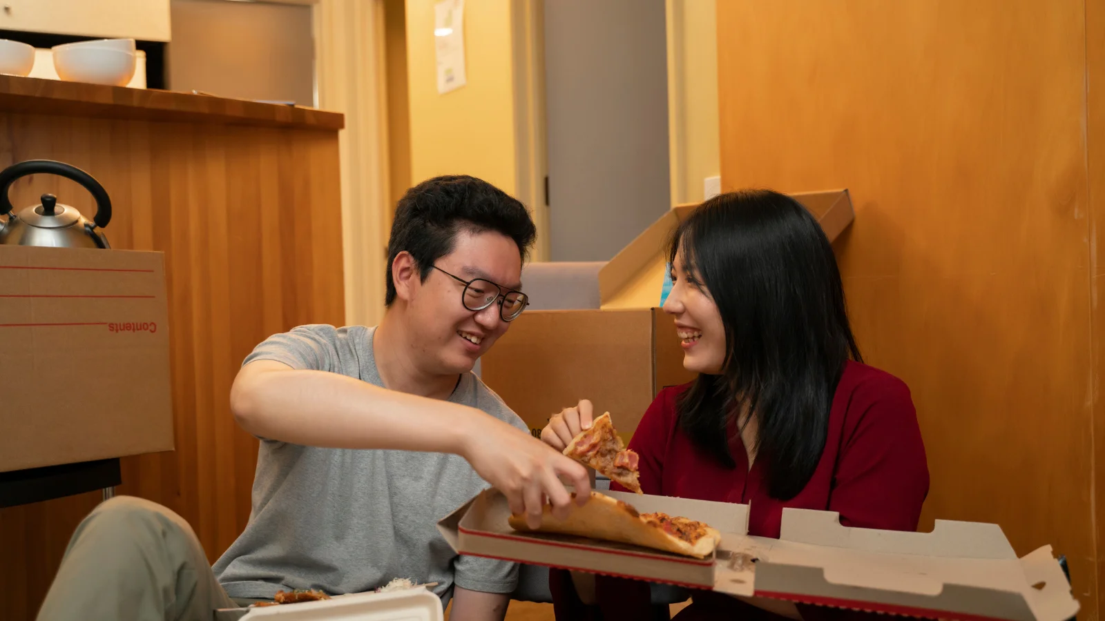 Couple eating pizza in new house.