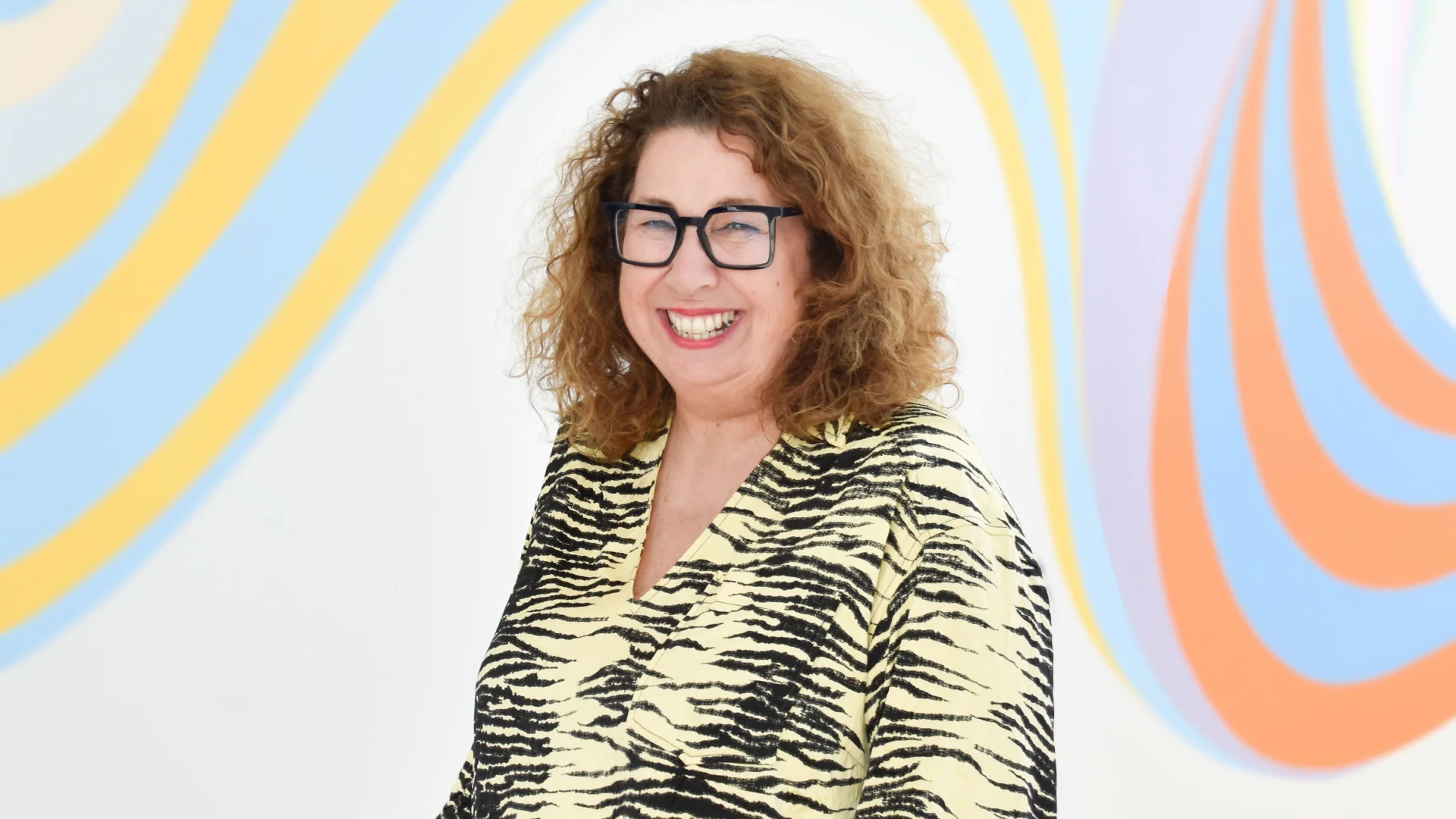 Annie Brown, Trade Me's Chief People Officer photographed in front of a Gina Kiel mural wall.