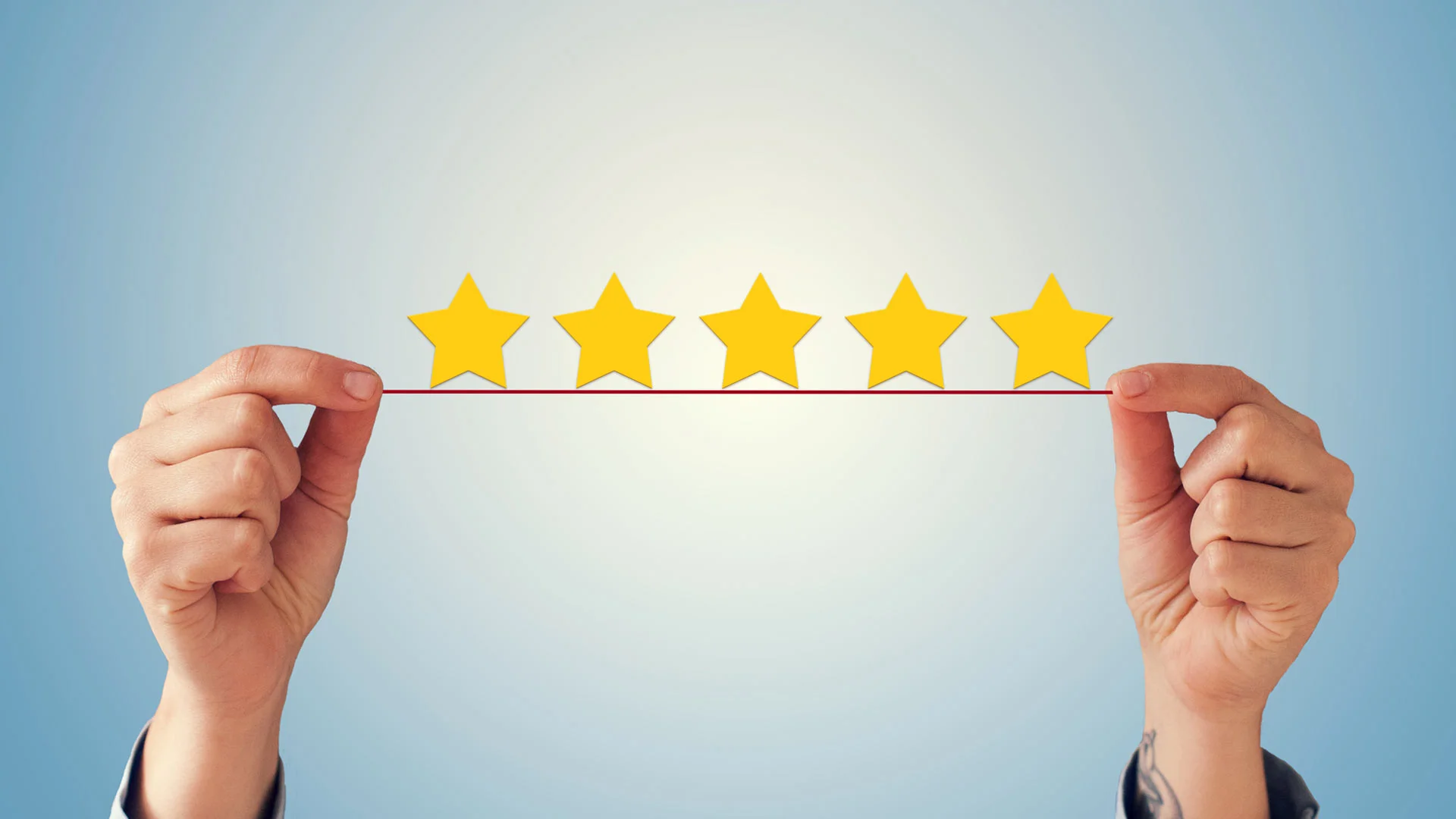 A pair of hands holdings up five small golden stars.