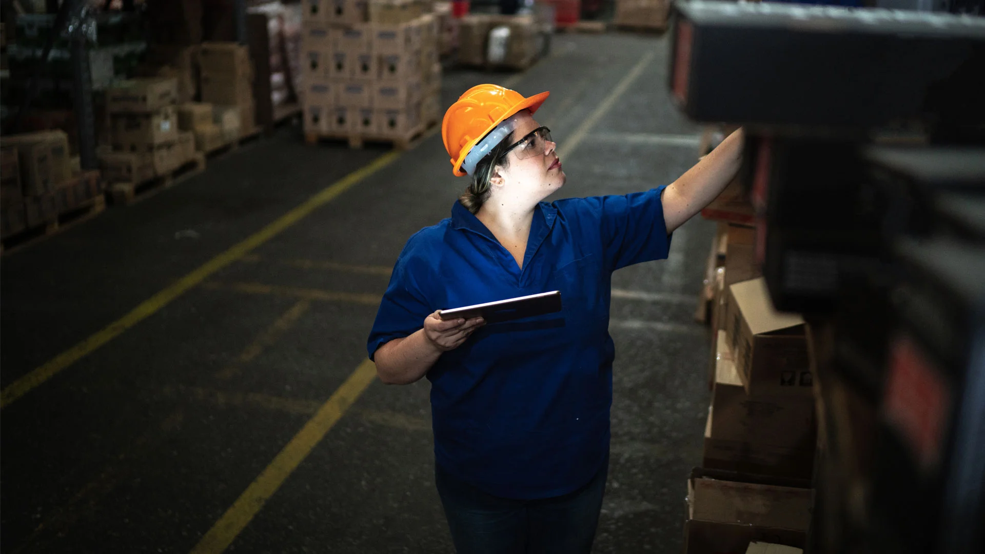 Supermarket worker working on the nightshift checkig deliveries using a tablet.