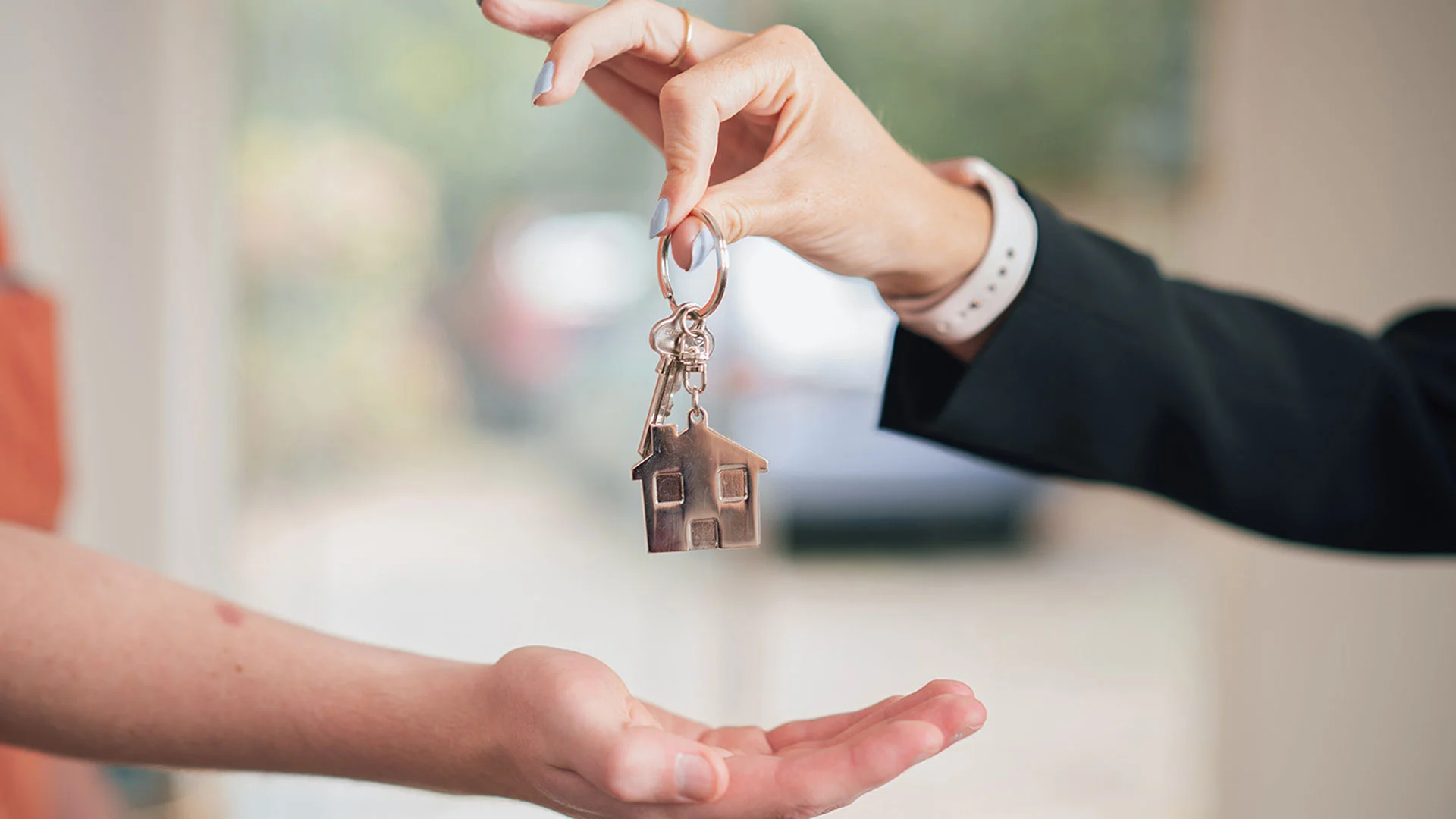 Real estate agent handing housekeys to a new home buyer.