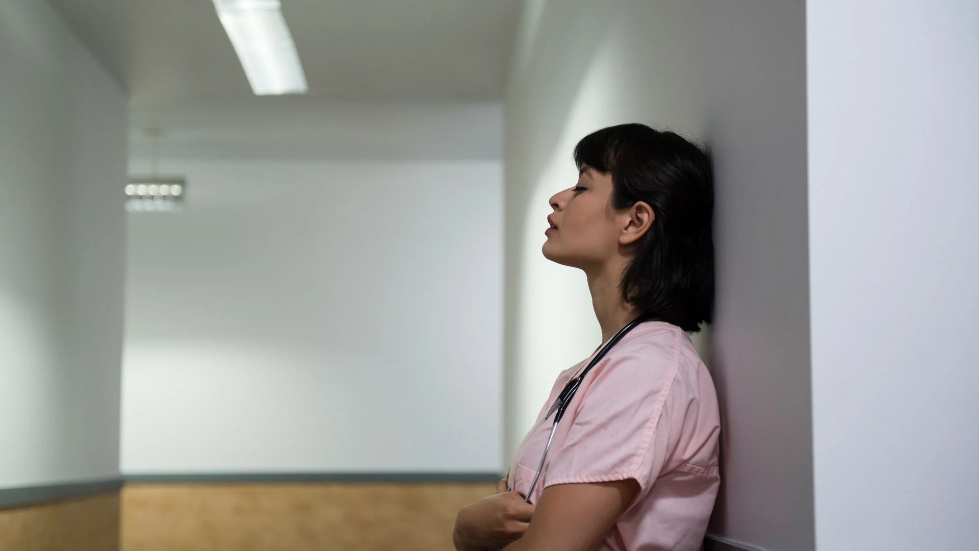 Tired doctor leaning against a wall.