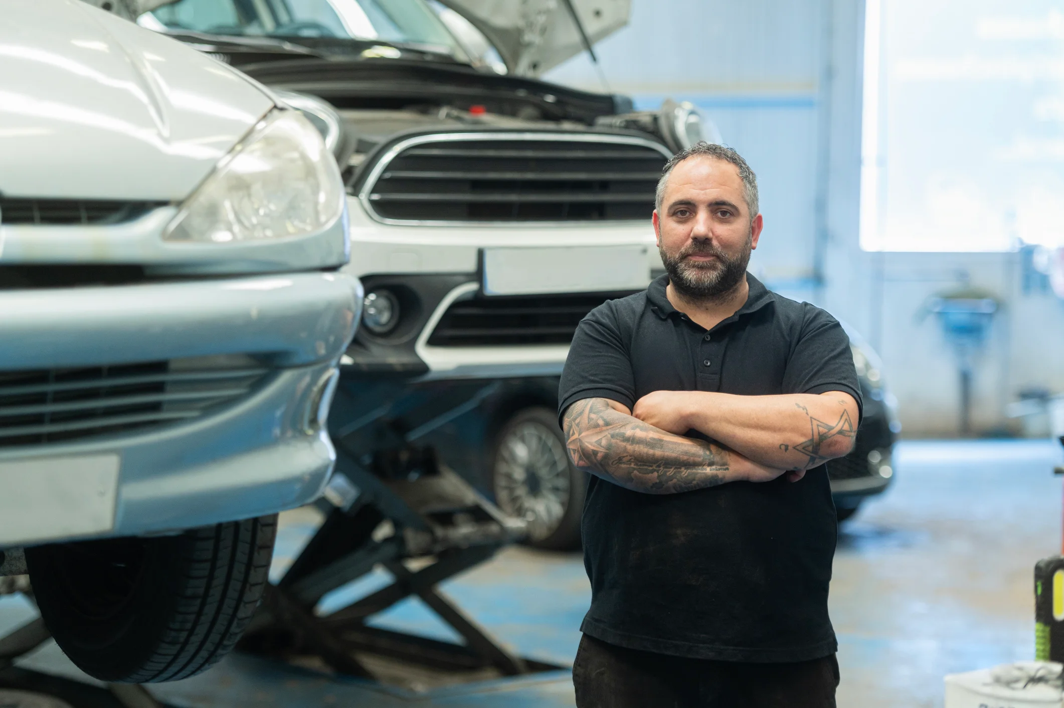 Man standing in front of cars at the repair shop. Mechanic.