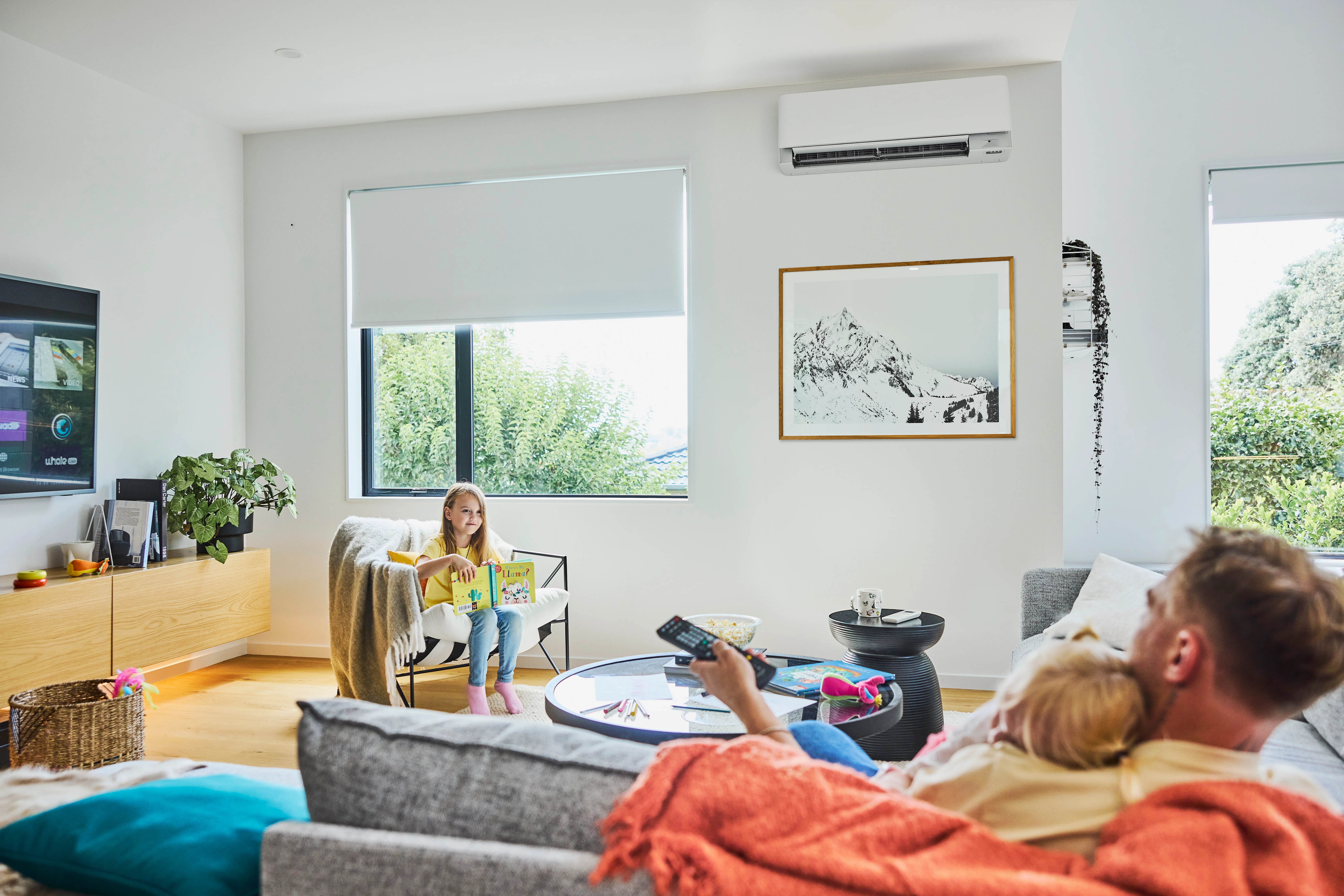 Dad holds baby on sofa while toddler talks to them