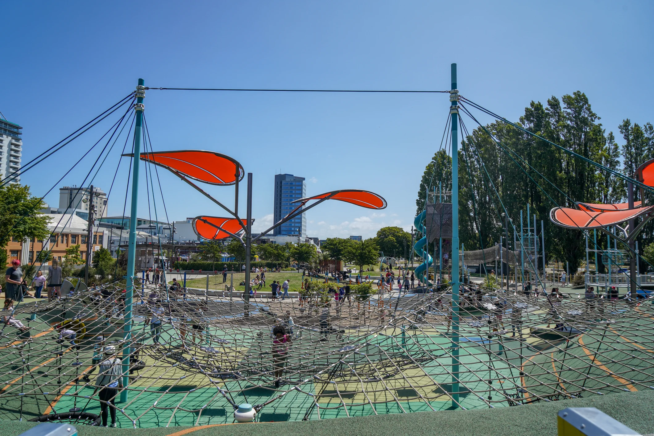 Playground with colourful covers and climbing frames under a blue sky.