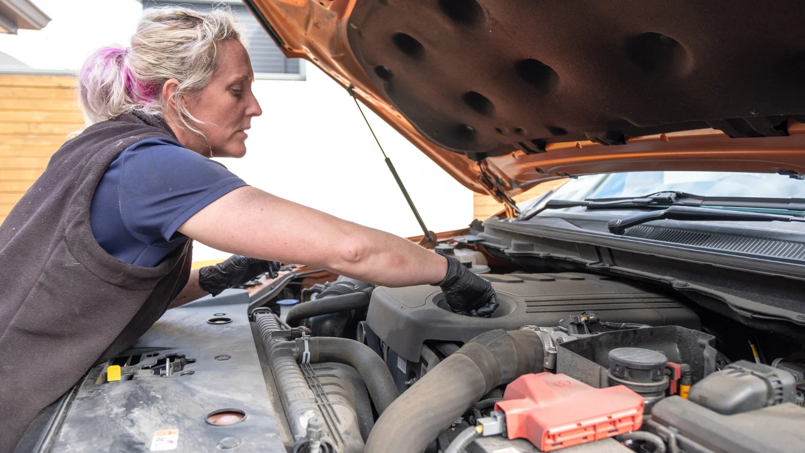 Female auto mechanic working on engine.