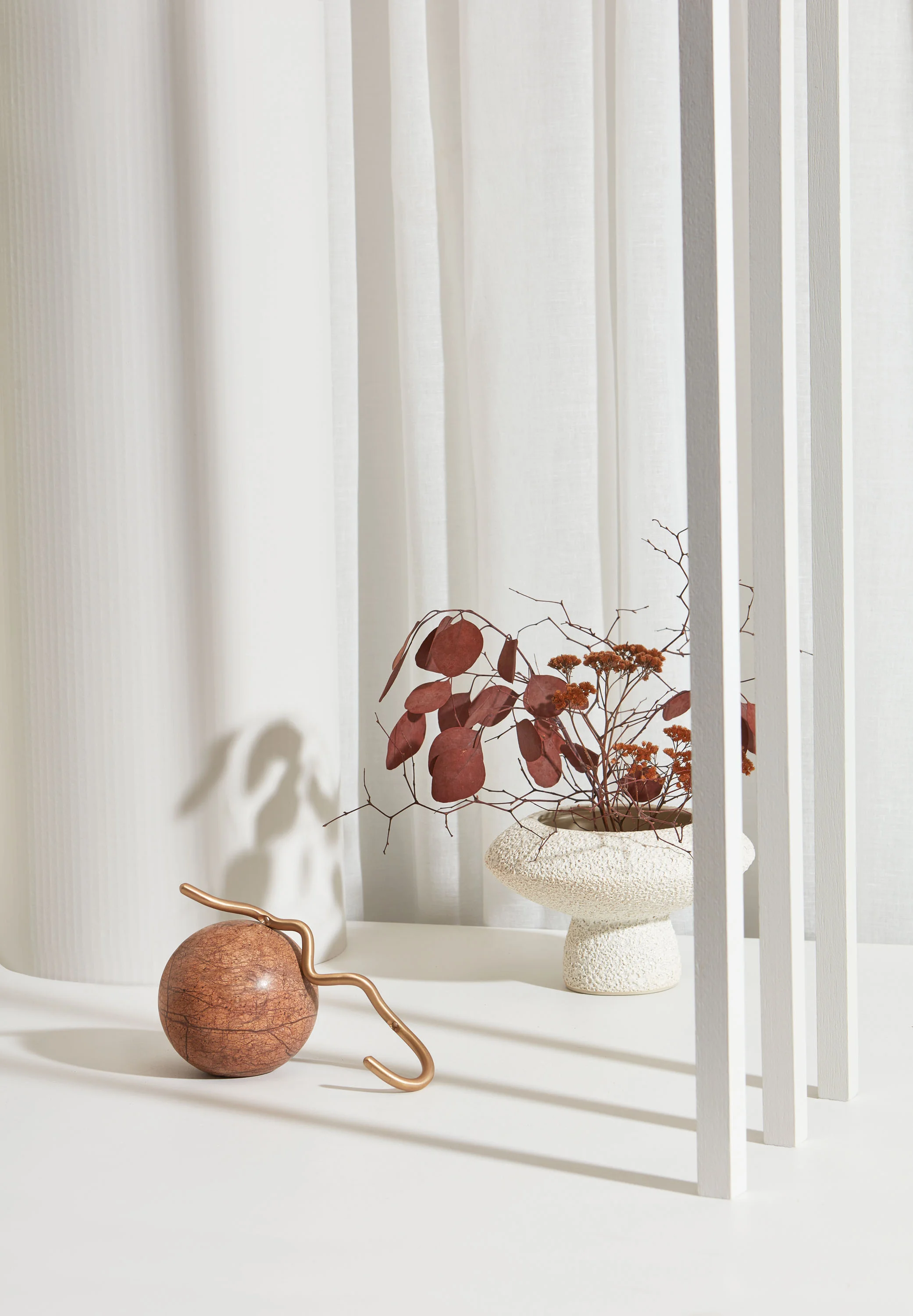  ABOVE: BACKDROP Left pillar in Resene SpaceCote Low Sheen White Pointer, flat surface in Resene SpaceCote Low Sheen Half White Pointer, slats in (from front) Resene SpaceCote Low Sheen Half White Pointer, Resene SpaceCote Flat Quarter Truffle and Resene SpaceCote Flat Half Cloud, resene.co.nz. Zepel Rhyme fabric in Pure (used as curtain), POA, jamesdunloptextiles.co.nz. DECORATIVE ITEMS, FROM LEFT Geo marble sphere, $80, cittadesign.com. Curvature hook by Ferm Living, $95; Lully vase by Marloe Marloe, $340, slowstore.co.nz.