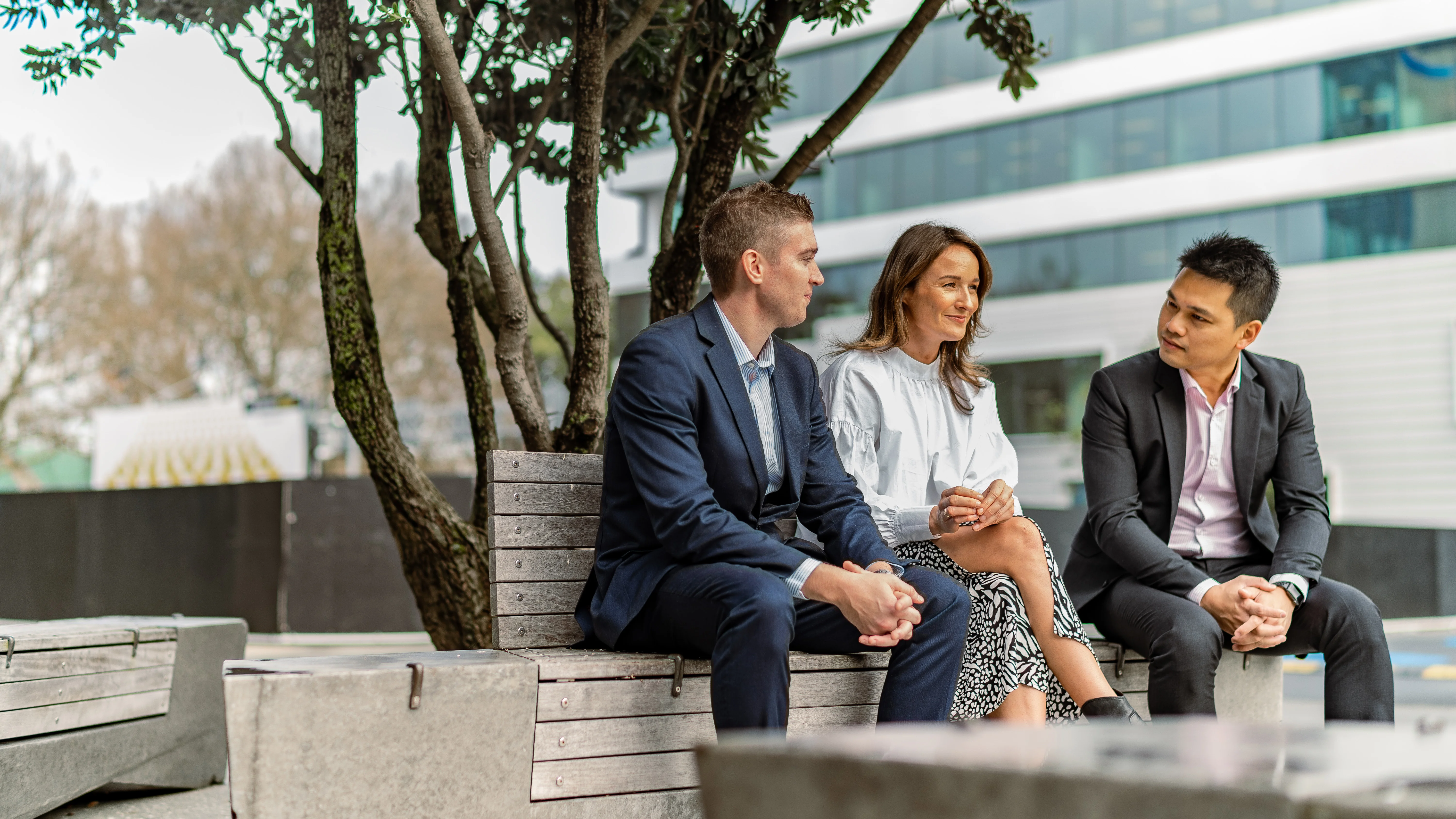Three employees sit having a discussion, one looking concerned.