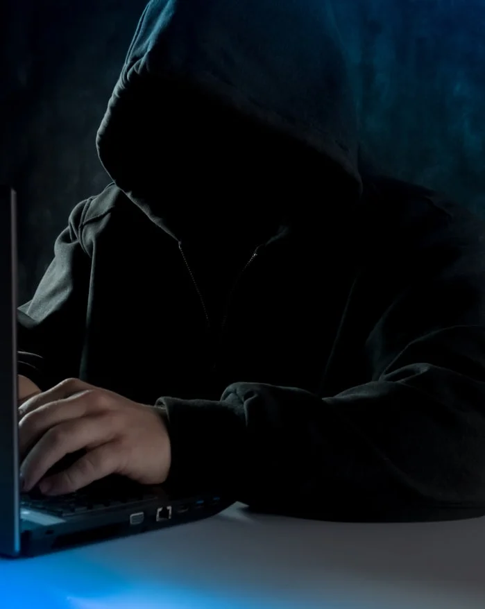 A hooded figure behind a laptop