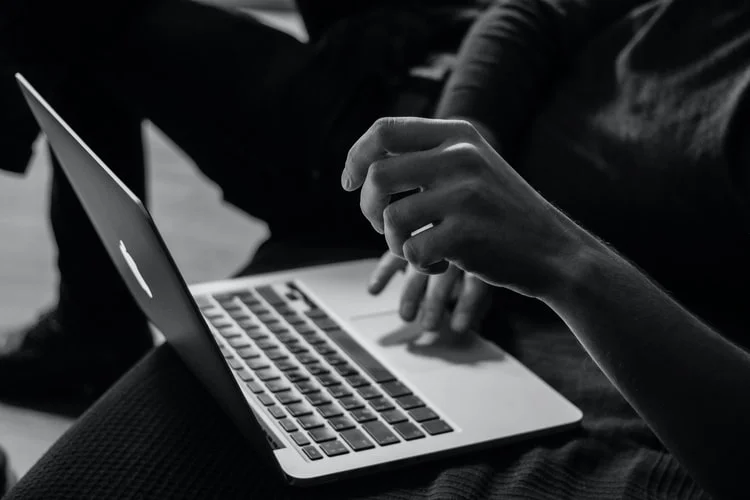 Black and white, low exposure photo of a person using a laptop.