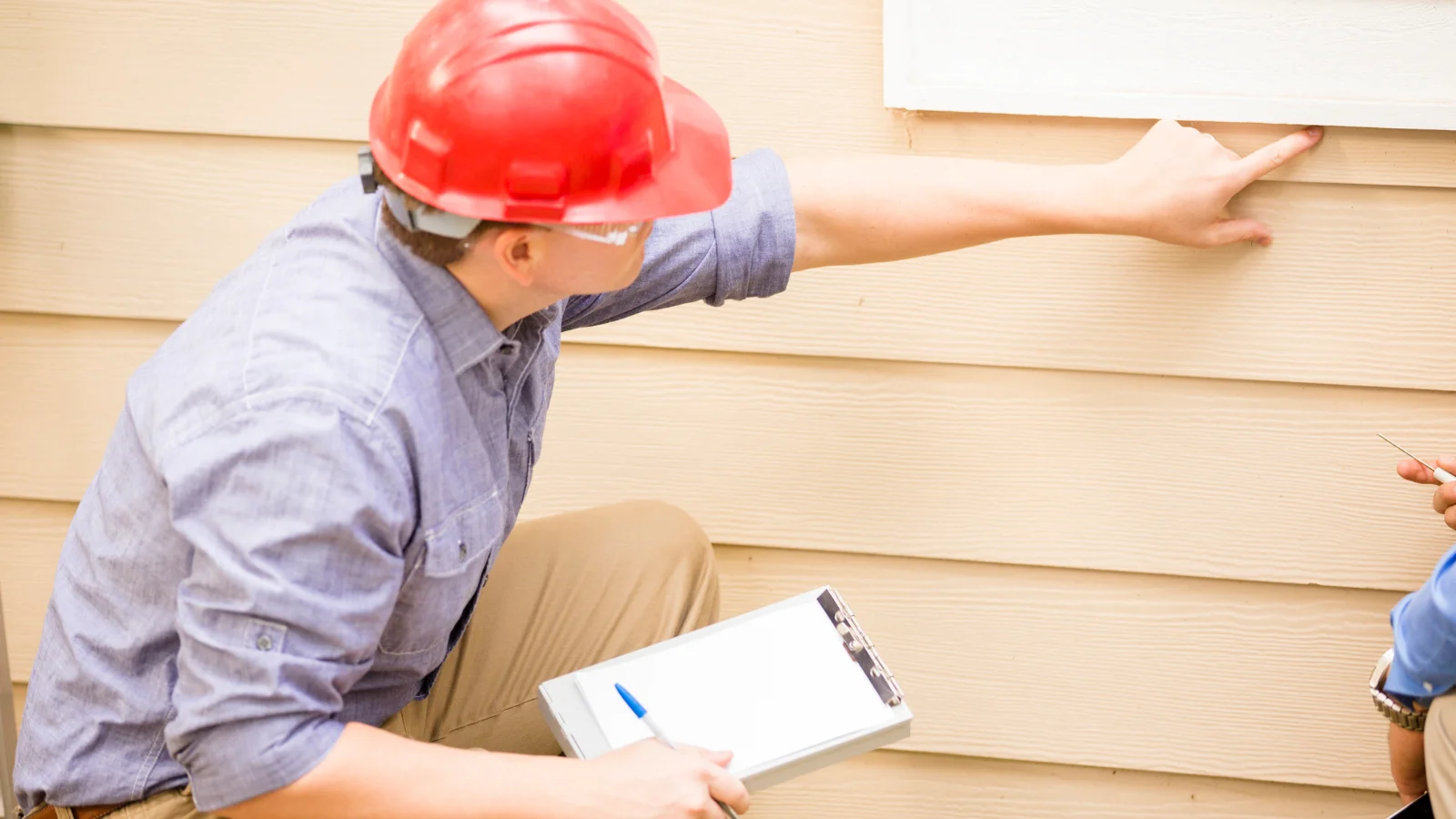 Building inspector in hard hat looking at property.