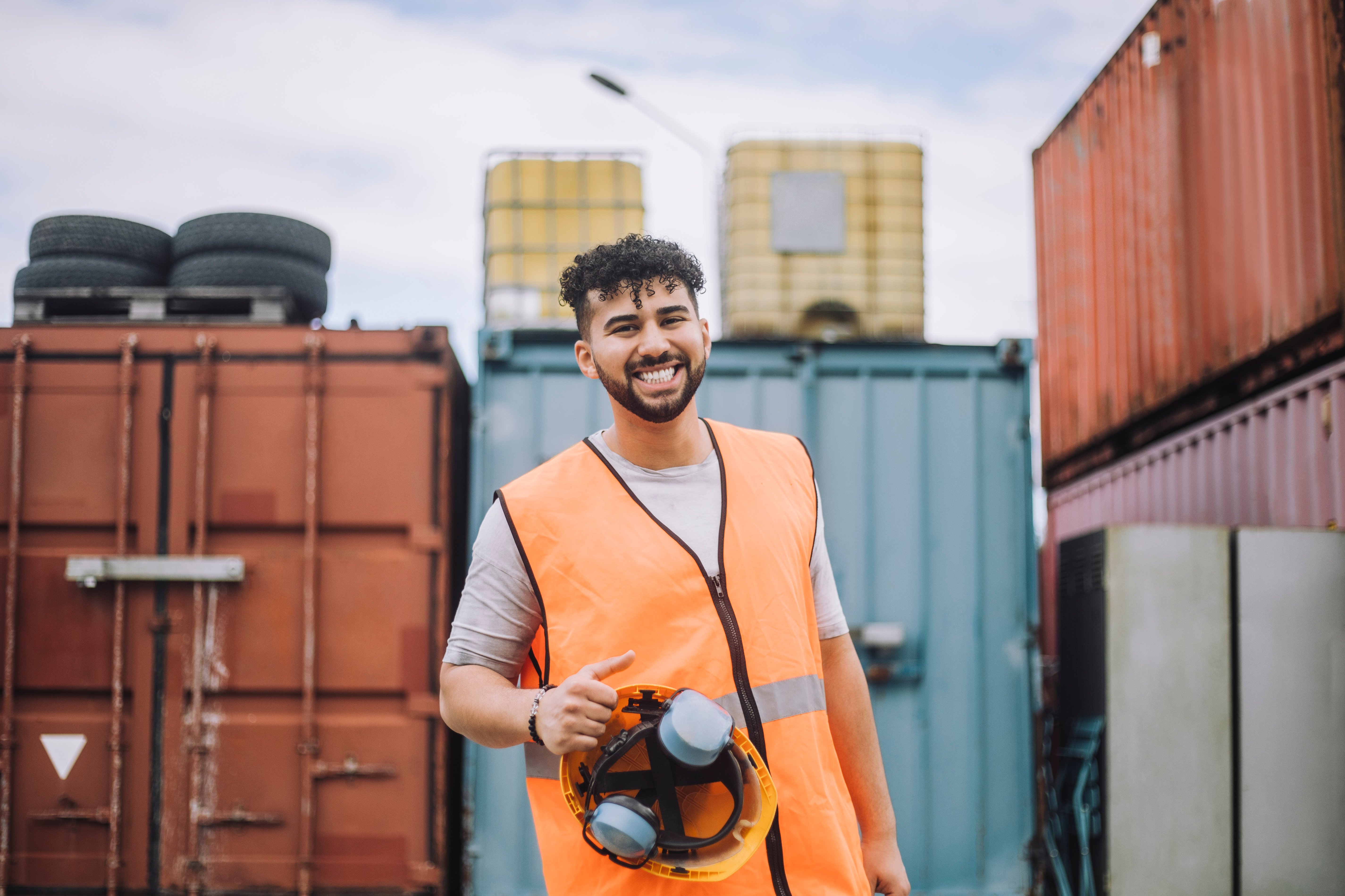 Man smiling while standing in front of shipping containers
