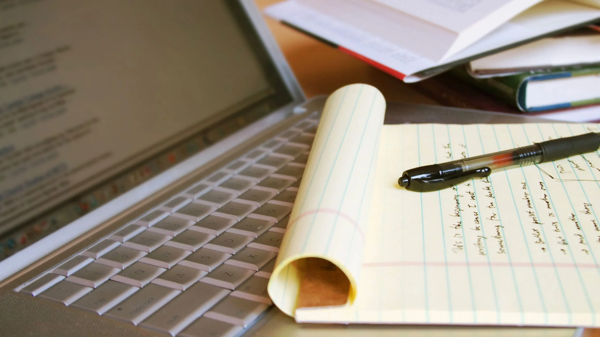 Notepad and pen resting on a laptop keyboard.