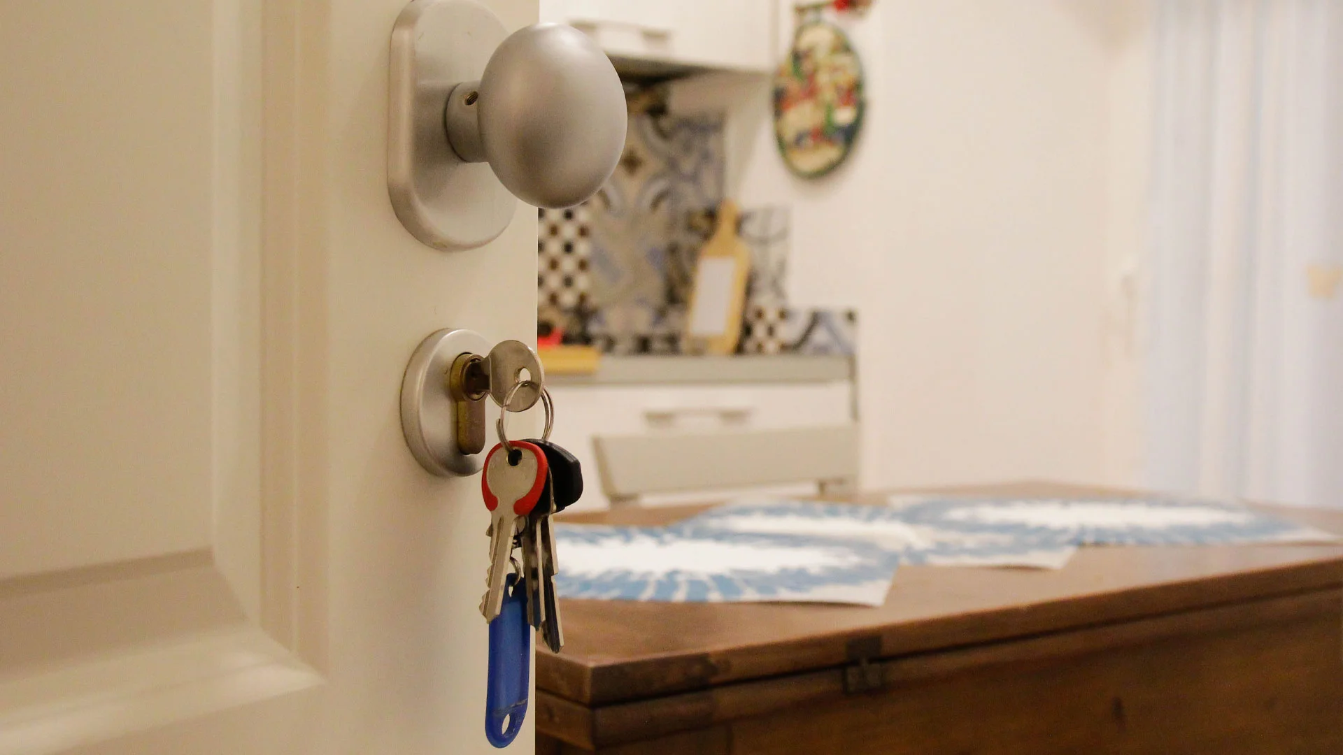 An open front foor with a set of keys in the lock.