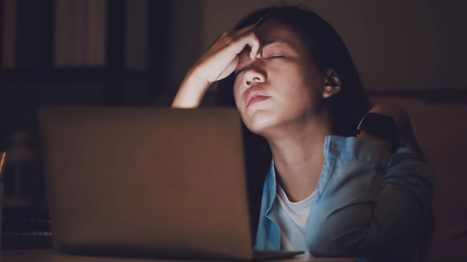 Stressed job hunter looking for jobs late at night on her laptop.