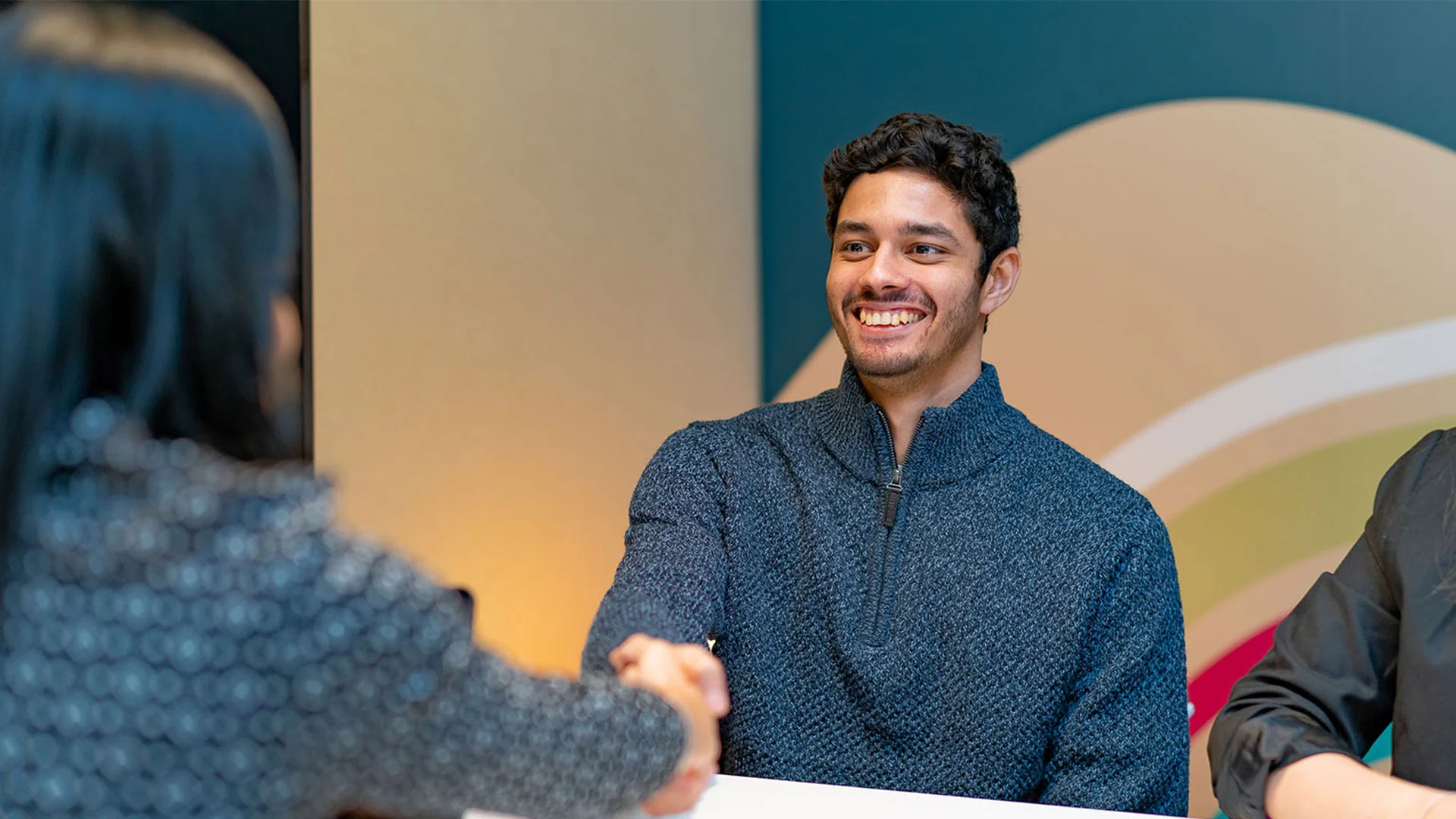 Young man starting a new job shaking hands with a colleague.
