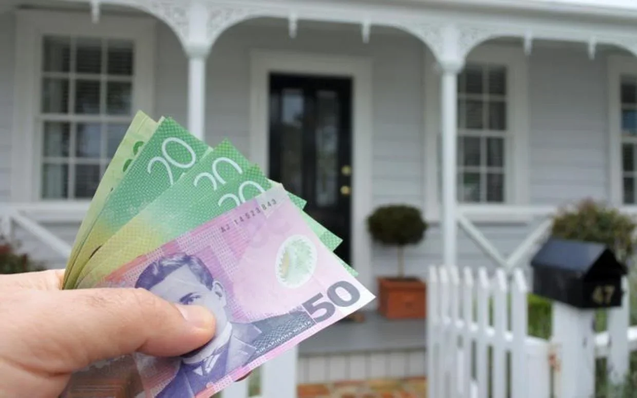 House in background, NZ cash in foreground