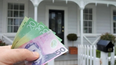 House in background, NZ cash in foreground