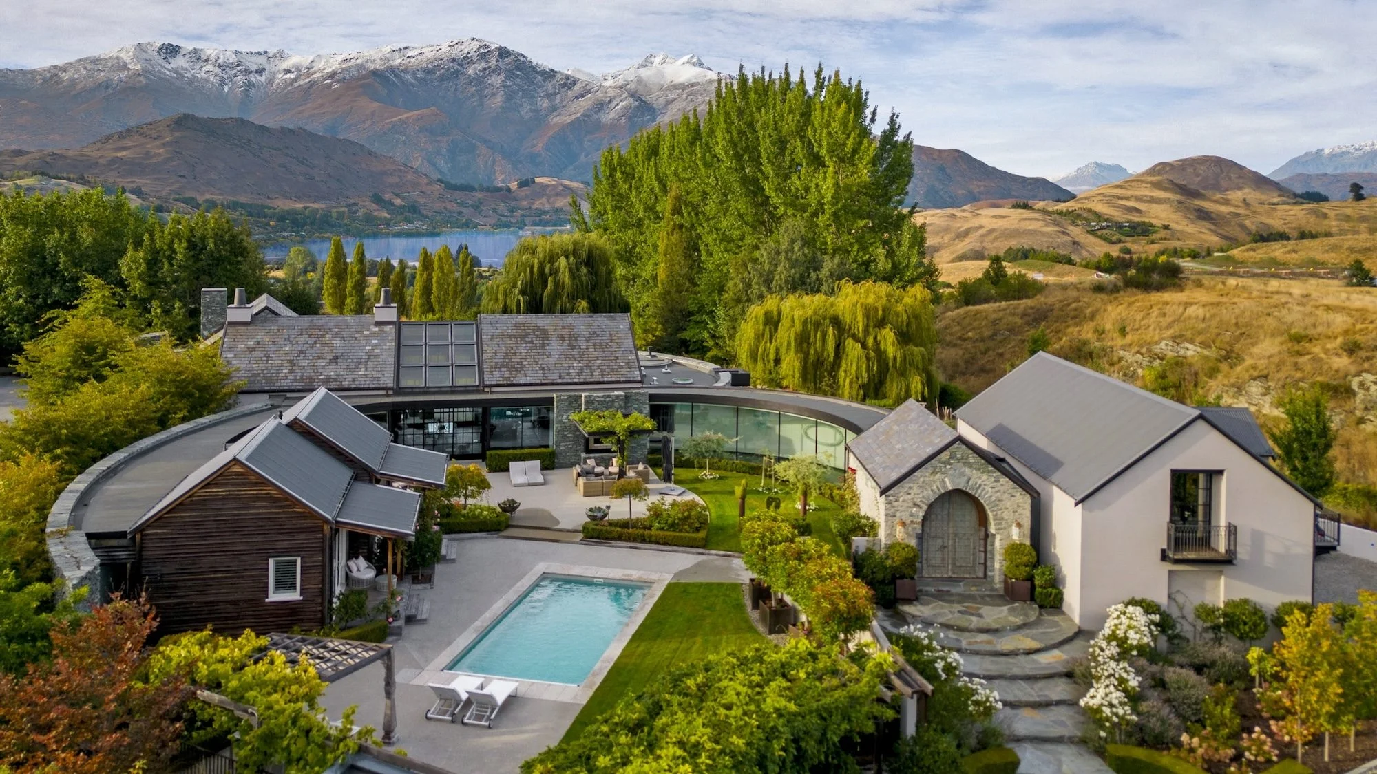 Luxury estate in Queenstown, one of the most expensive houses in New Zealand, with modern stone architecture, landscaped gardens, swimming pool, and panoramic mountain views.