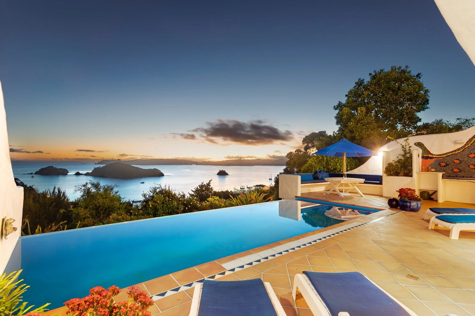 Luxury home with an infinity pool overlooking the Bay of Islands, surrounded by lush greenery and panoramic ocean views stretching the horizon.