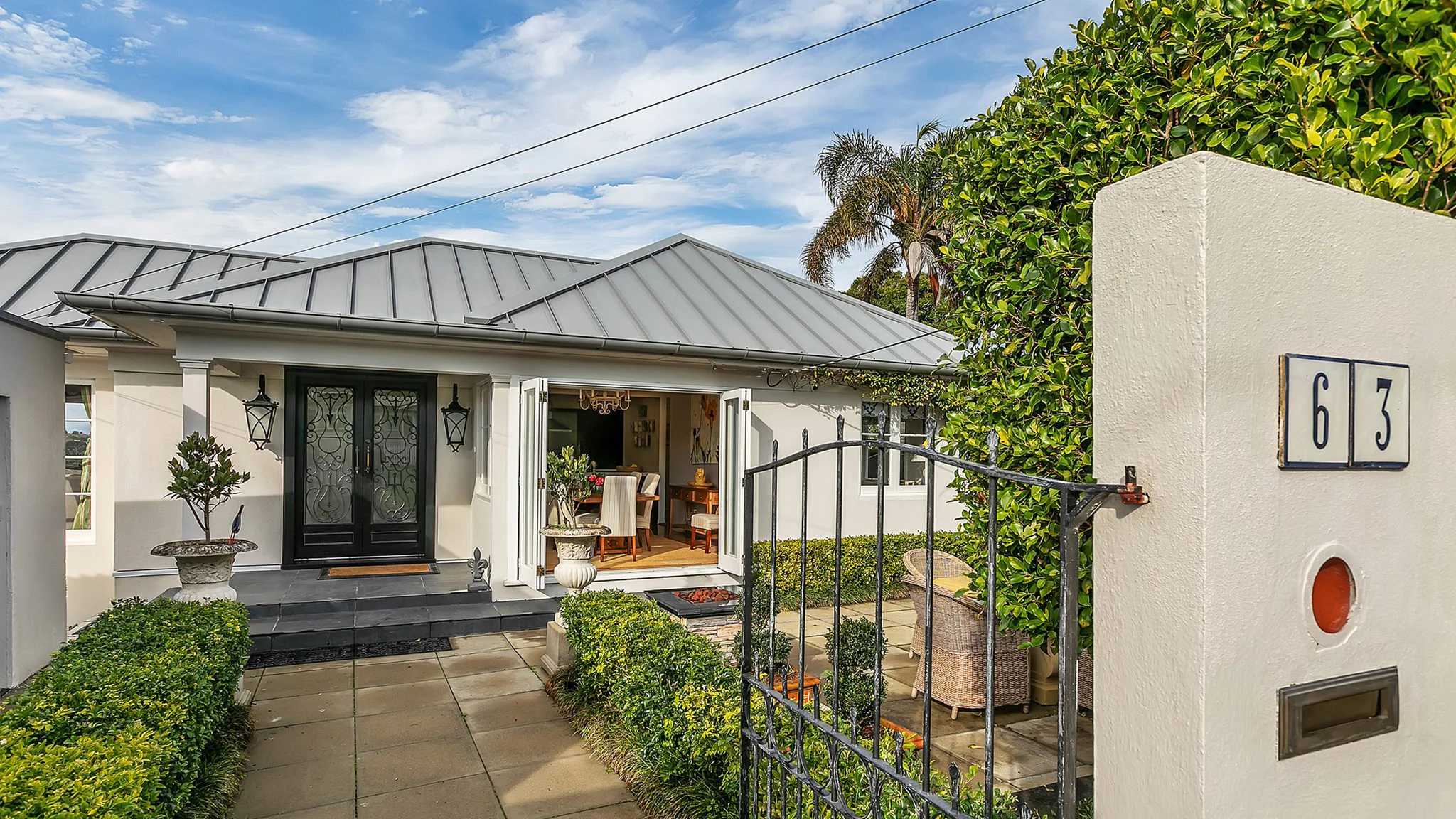 Front view of white house with paved path and gate.