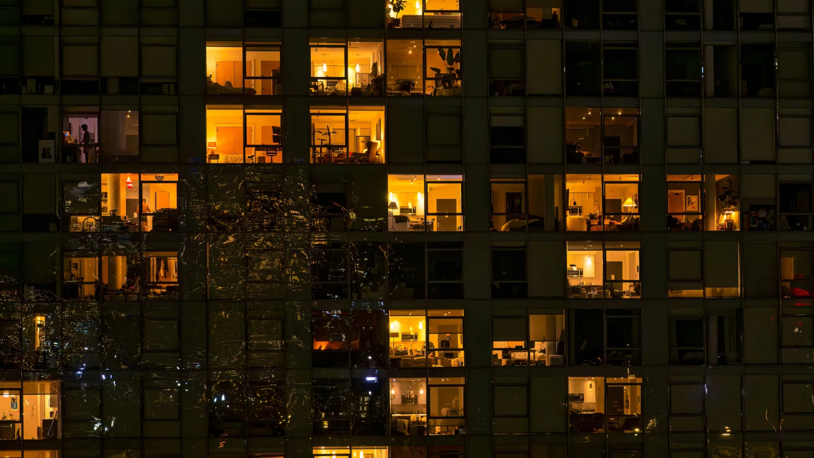 Image of apartment building with lights on at night.