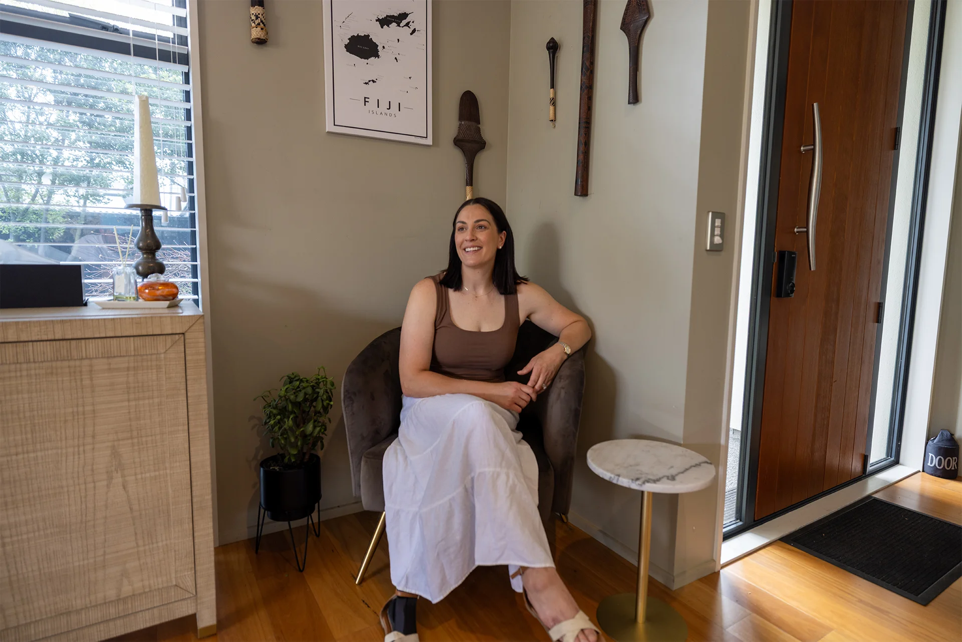 Sophie Pascoe sitting below Fijian sculptures in a corner of her Christchurch home.
