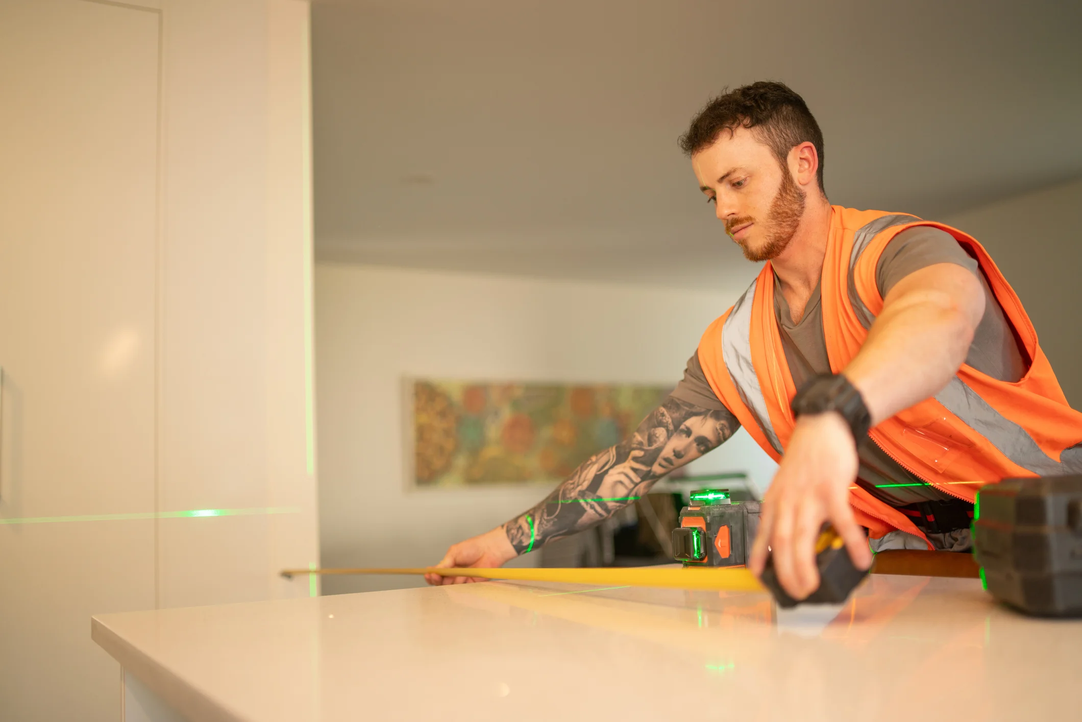 Young male tradesmen measuring on a bench top with a level and measuring tap