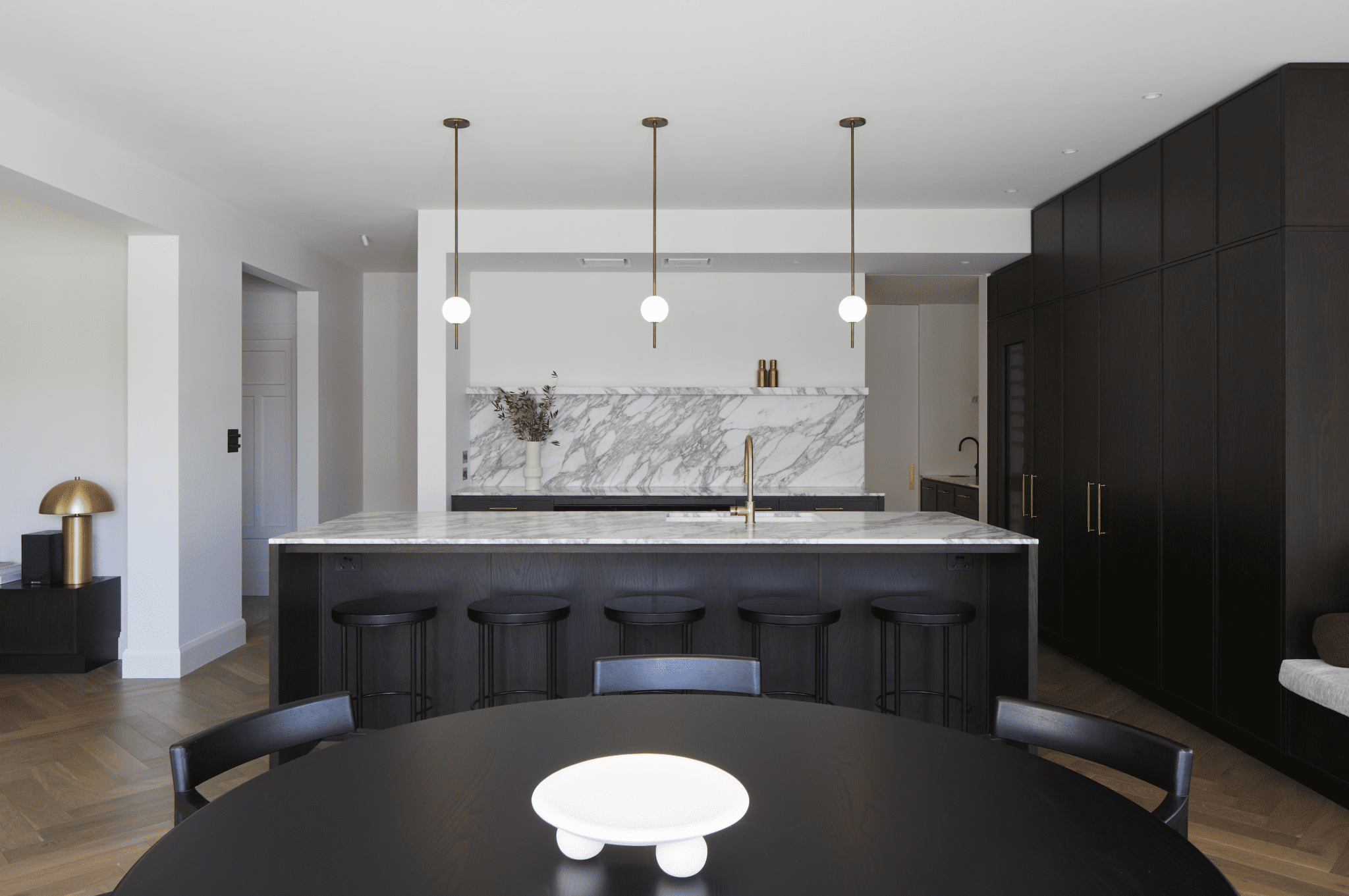 Modern black kitchen with sleek cabinetry, featuring three pendant lights hanging above the central island.