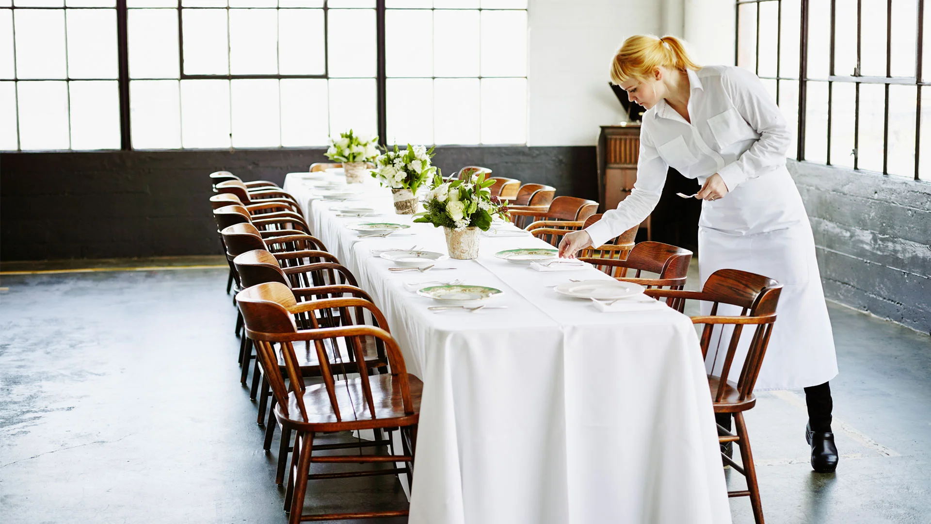 Young events worker laying the table of a posh dinner ahead of the guests arriving.